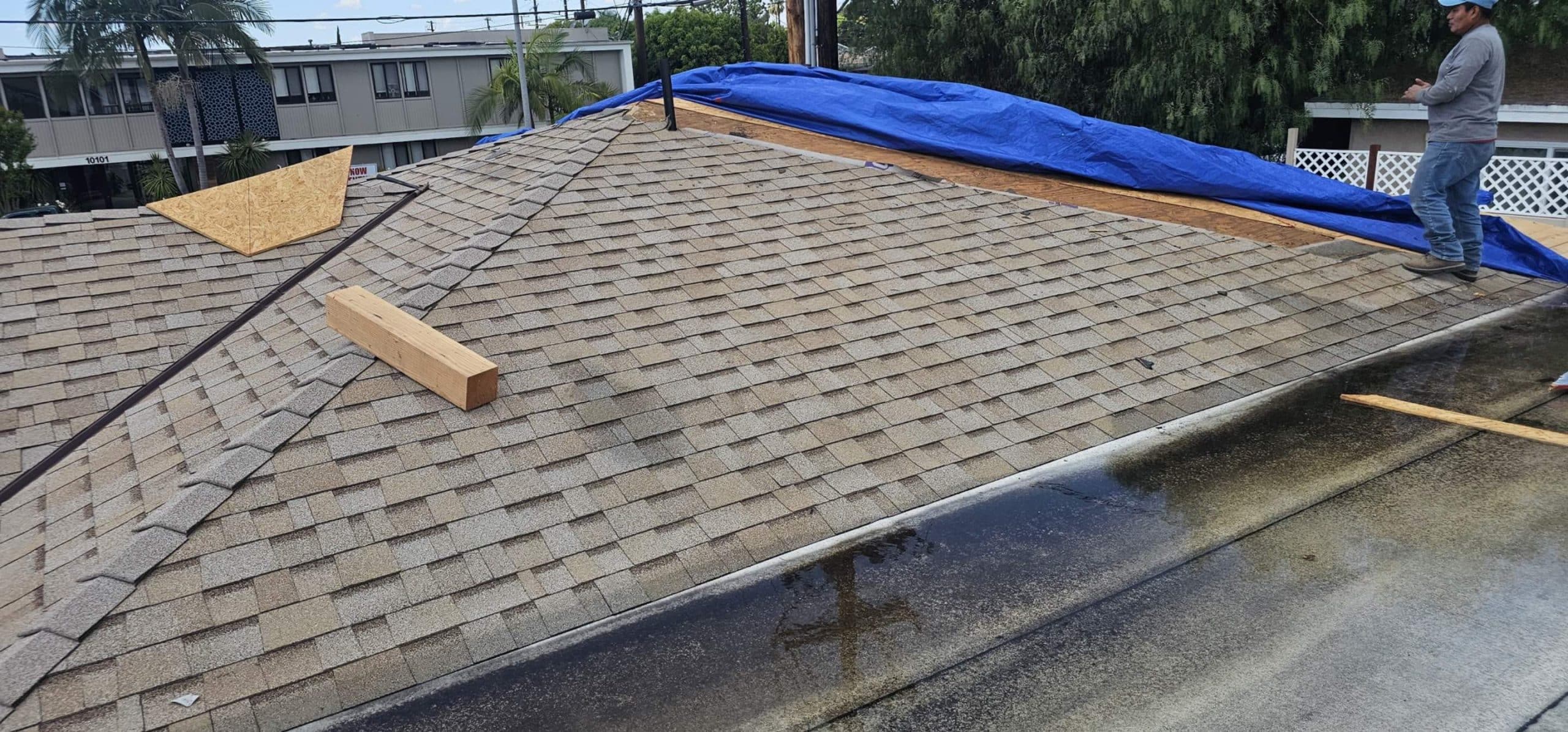 Residential roof repair with tarp and lumber