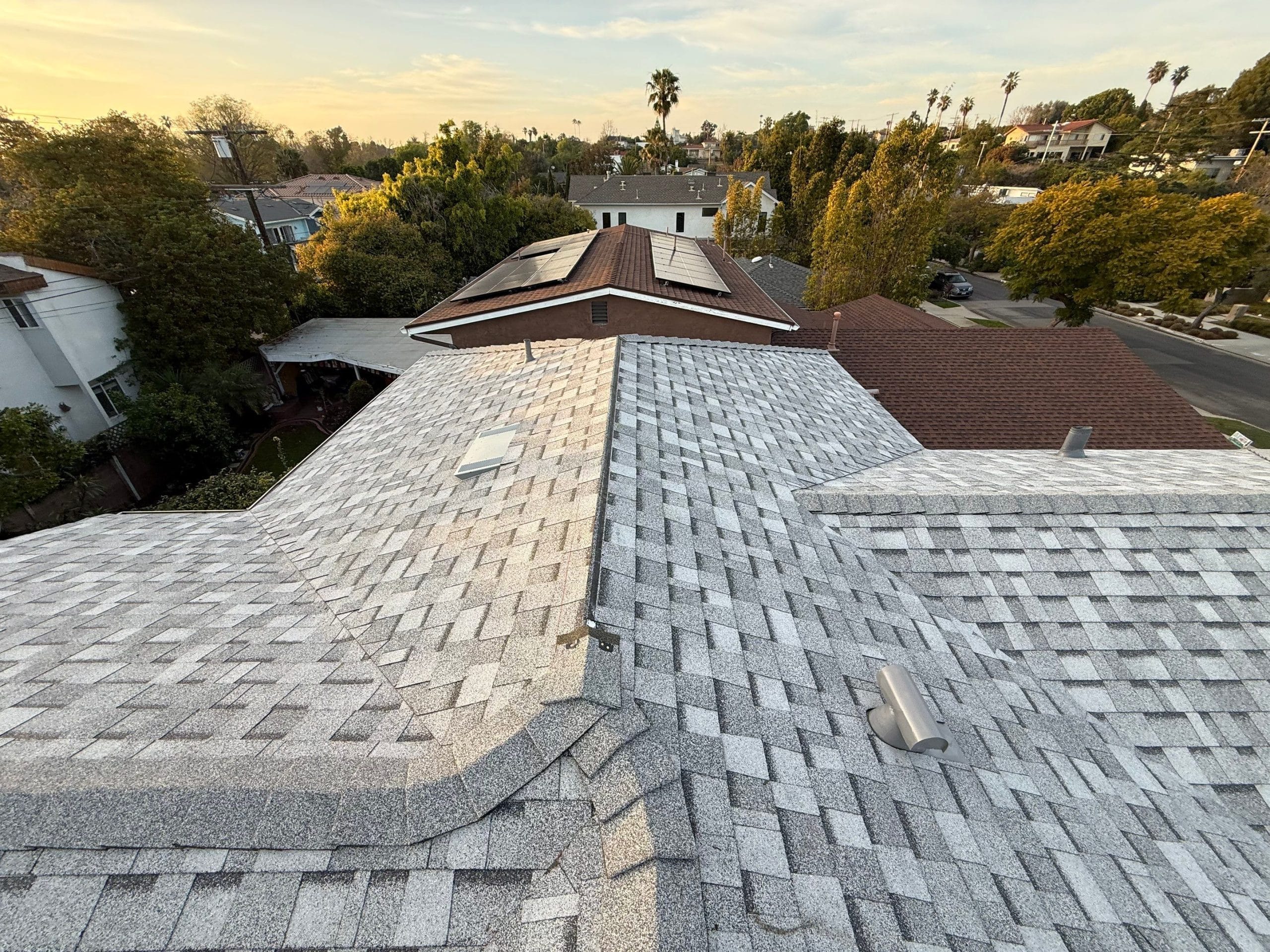 Gray shingle rooftop overlooking suburban neighborhood at sunset