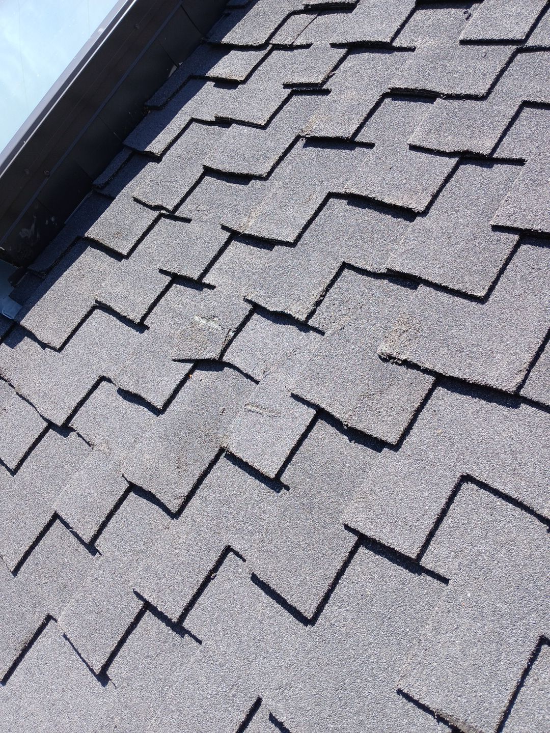 Damaged gray asphalt roof shingles close-up