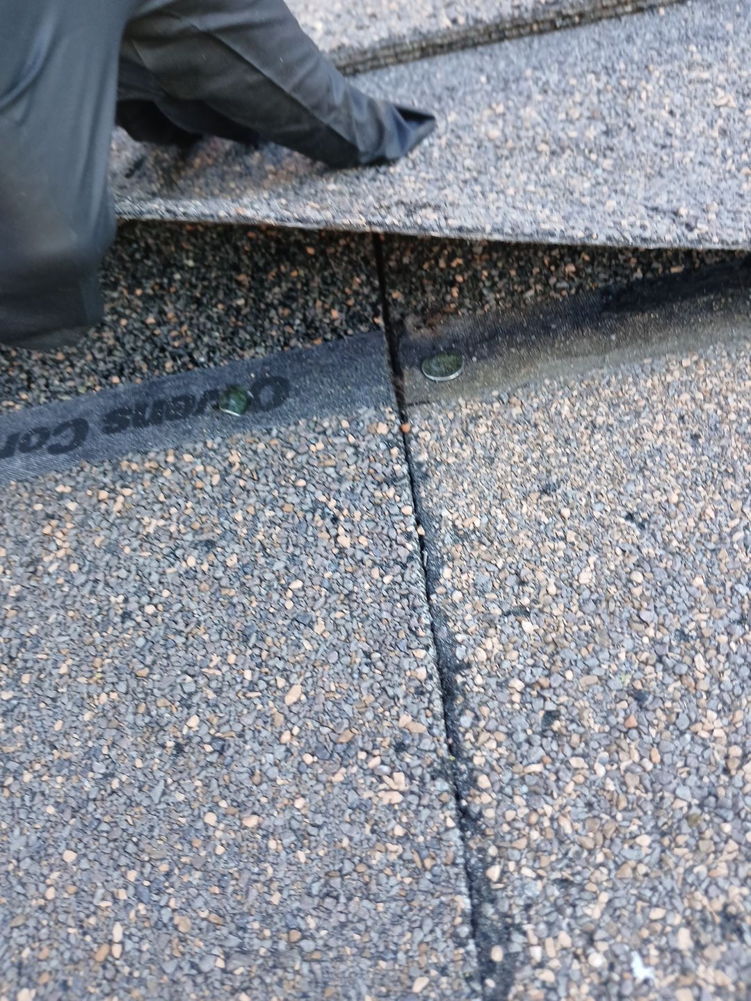 25-Mar 17 2026 08_05am-HeU5 Gloved hand lifting asphalt roof shingles