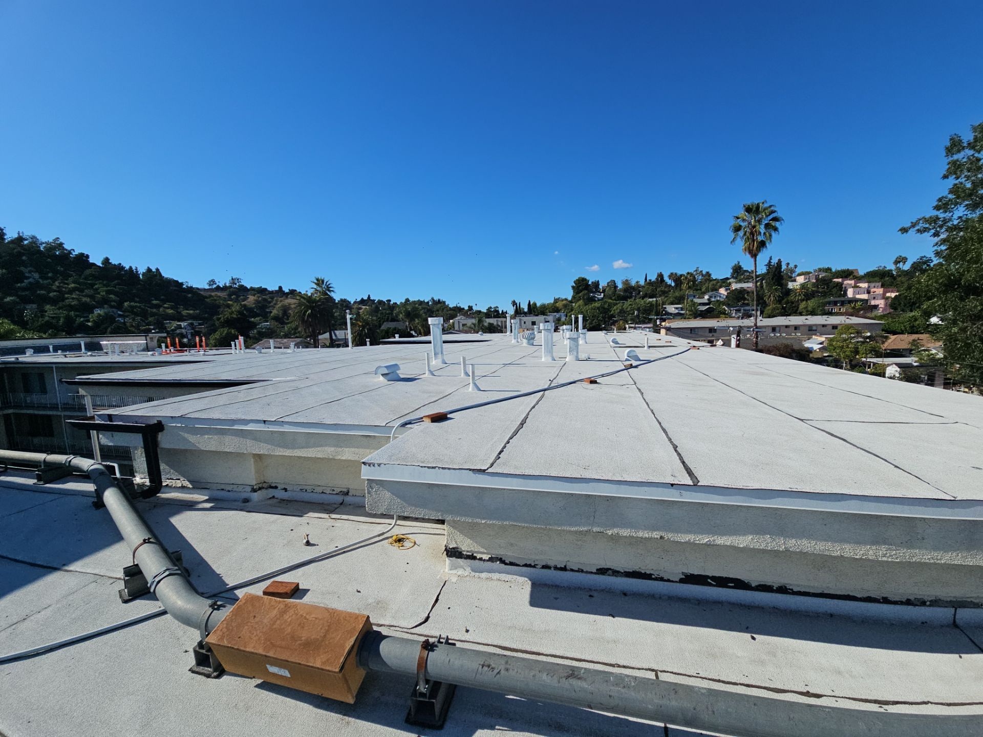 Flat white rooftop with vents and hillside view