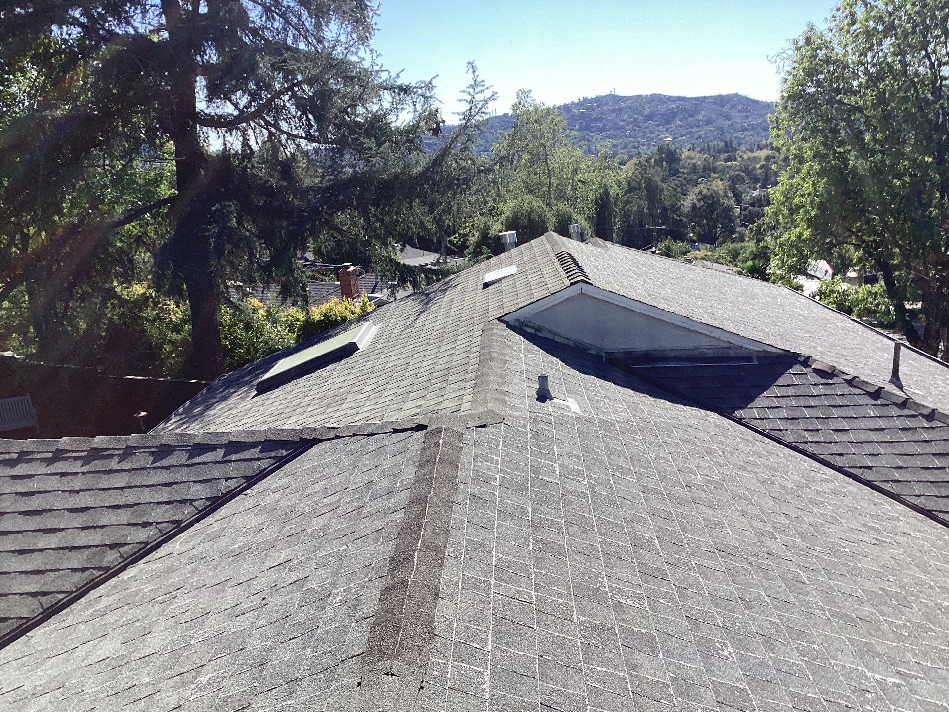 Residential shingle roof with skylight and hillside view
