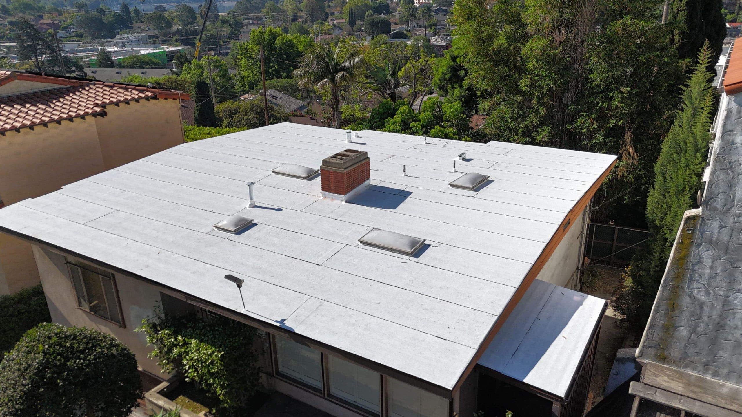 Flat white residential roof with chimney and vents