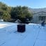 Worker repairing white flat roof with mountains behind
