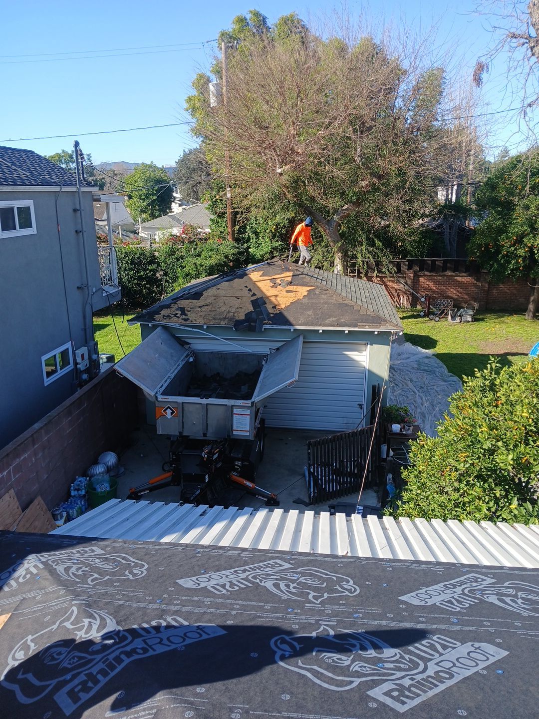 Worker removing shingles from residential garage roof