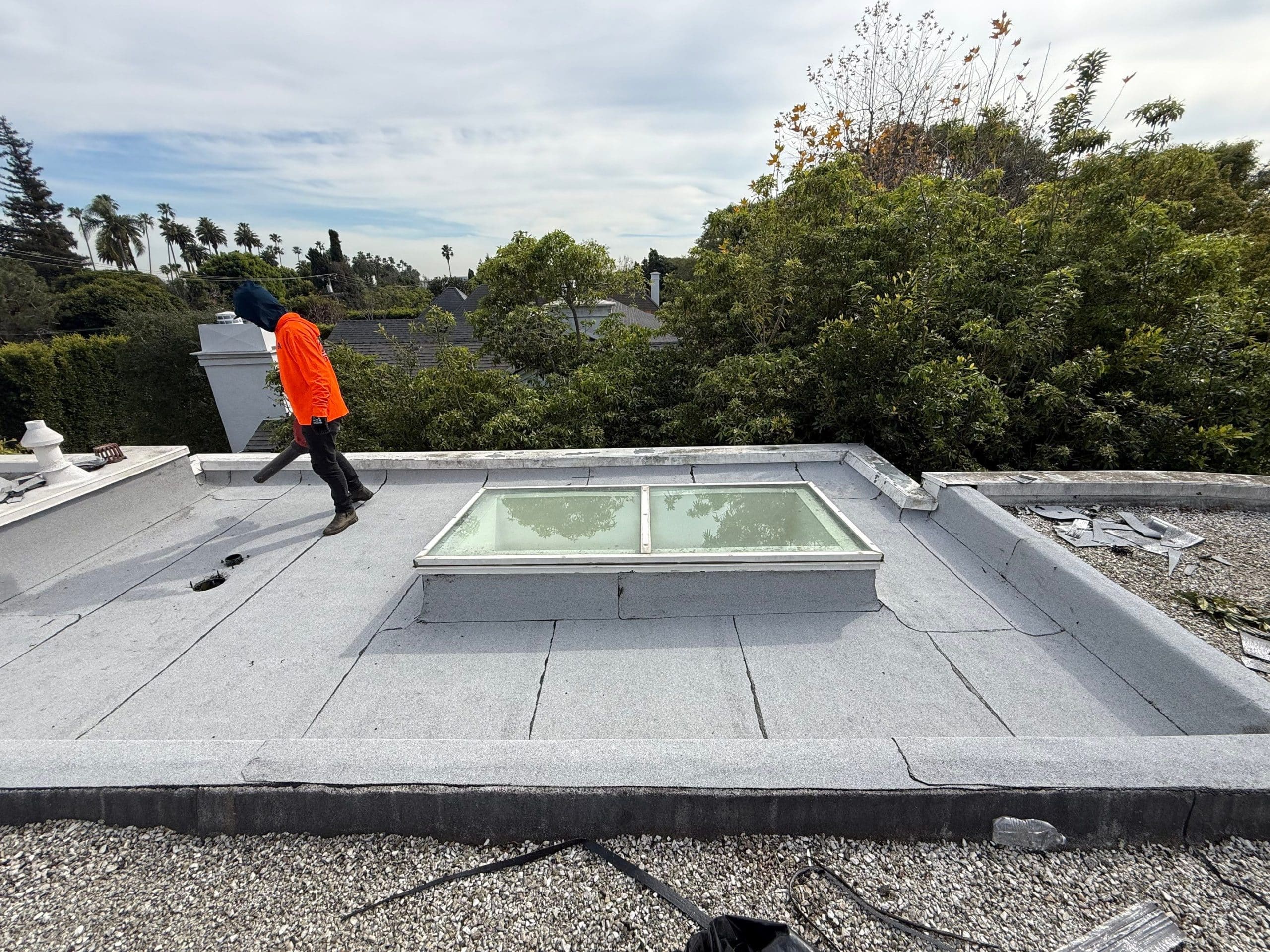 Worker using leaf blower on flat rooftop