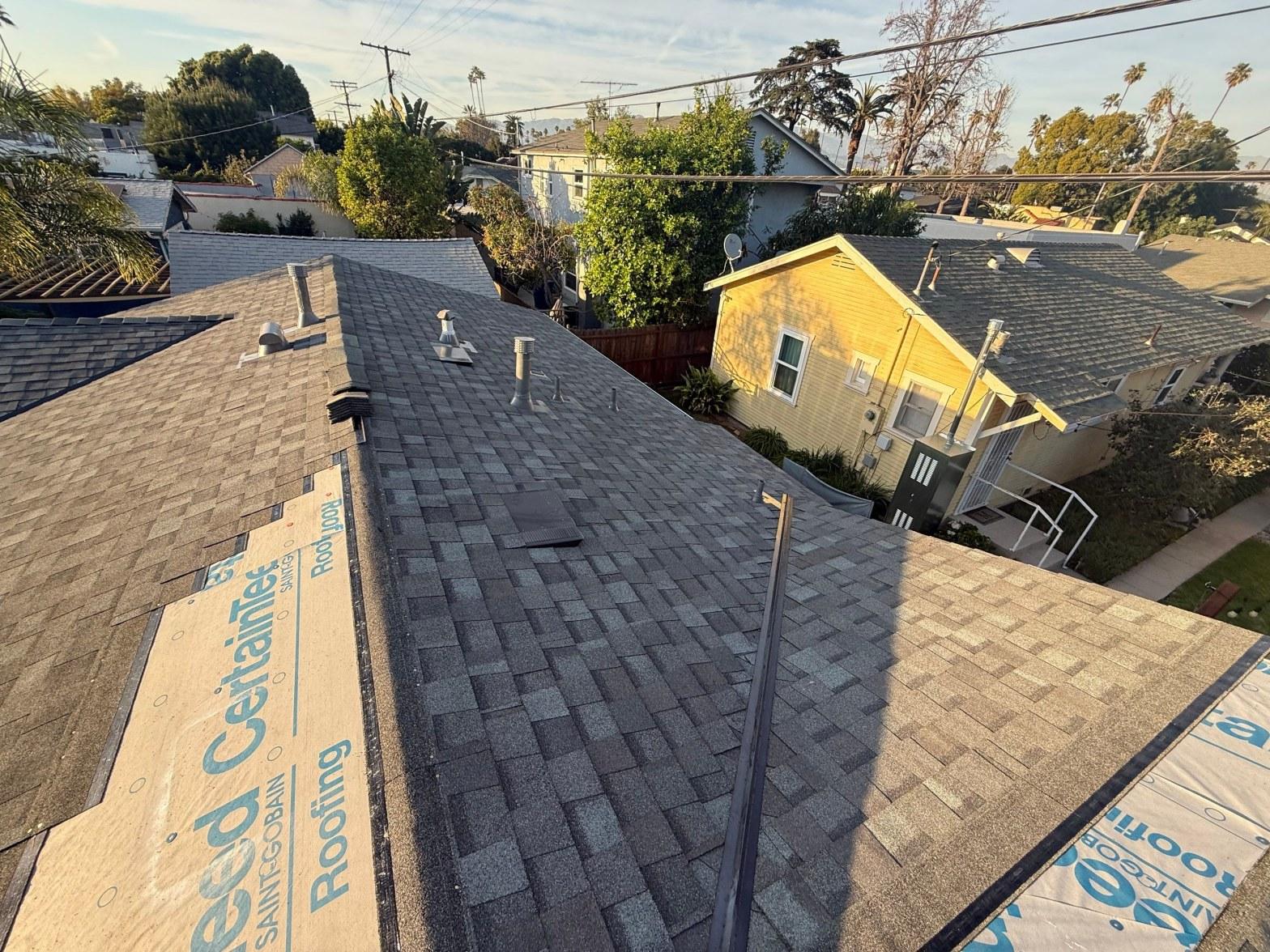 CertainTeed roofing underlayment and new dark gray asphalt shingles on residential home roof with pipe vents.
