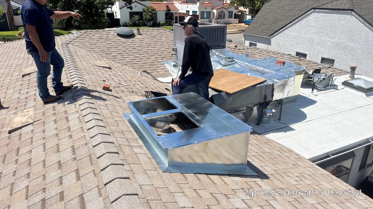carrier-rooftop-package-unit-installation-burbank-ca-824 Two HVAC technicians on rooftop installing galvanized sheet metal plenum box next to AC condenser unit.