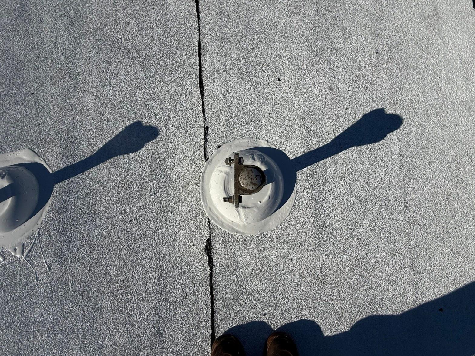 foam-roof-coating-flat-commercial-roof-los-angeles-perlita-a-1006 White elastomeric coated flat roof with metal fastener plates and hairline crack running between them.