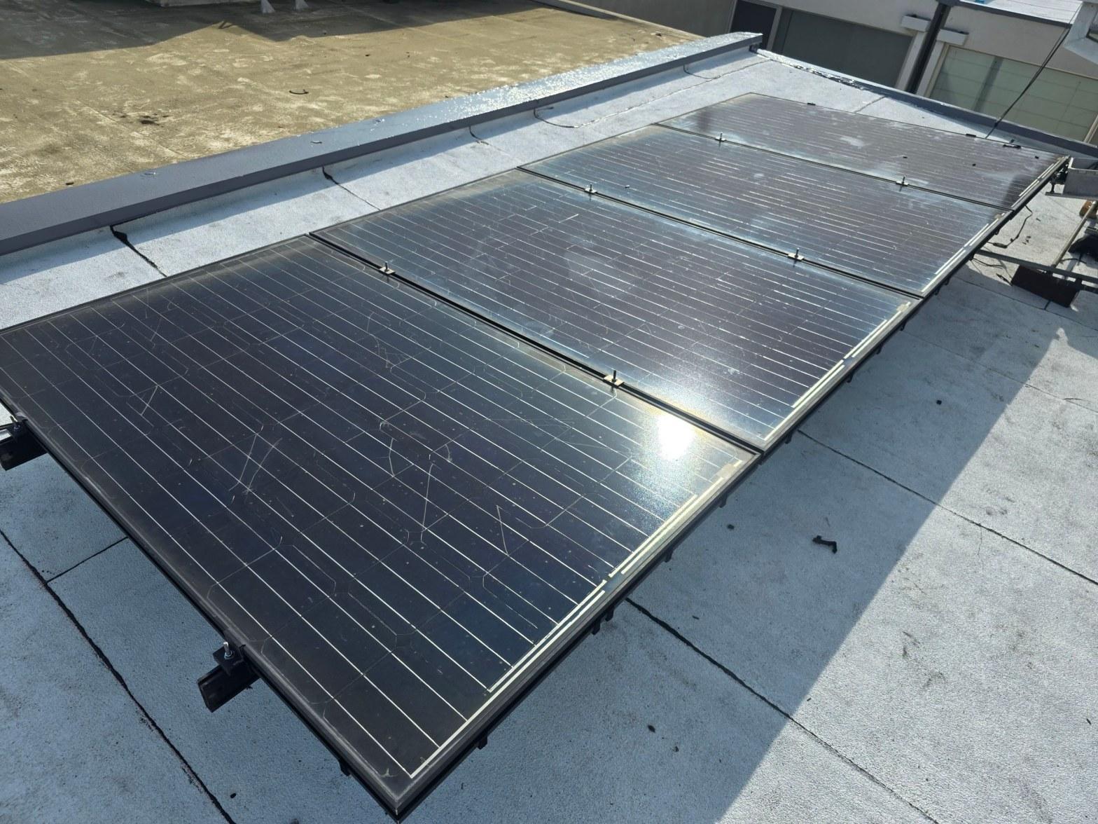 foam-roof-coating-flat-commercial-roof-los-angeles-perlita-a-986 Six monocrystalline solar panels installed on flat commercial rooftop with aluminum railing mounting system.