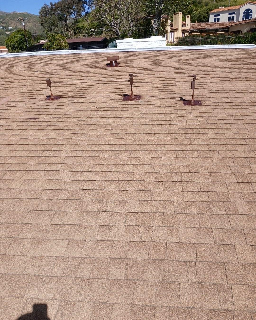 Tan asphalt shingle roof with three plumbing pipe boots and one mushroom-style roof vent installed mid-slope.
