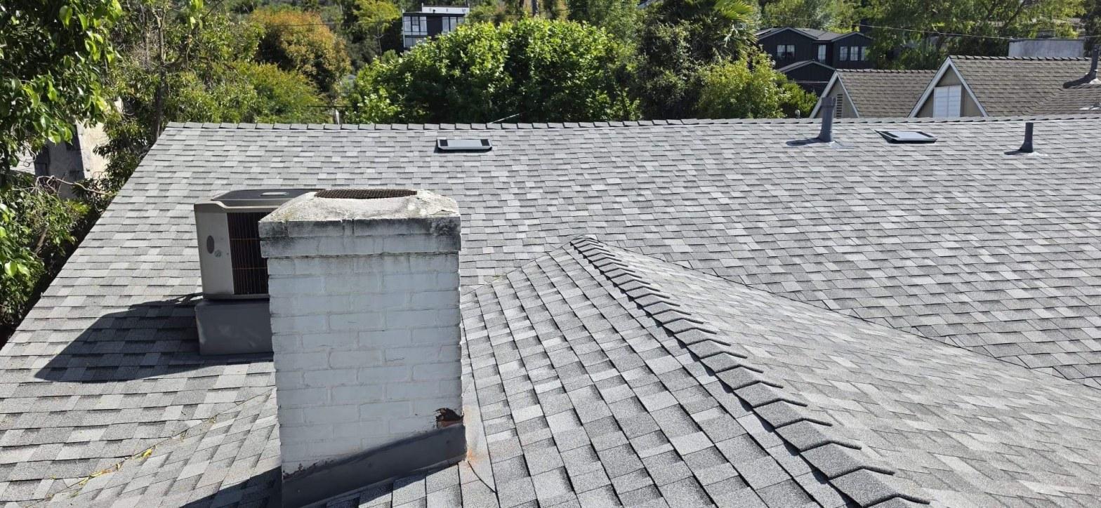 Gray asphalt shingle reroof on Los Angeles home showing white brick chimney, HVAC unit, and multiple roof vents — 14819 Sutton St