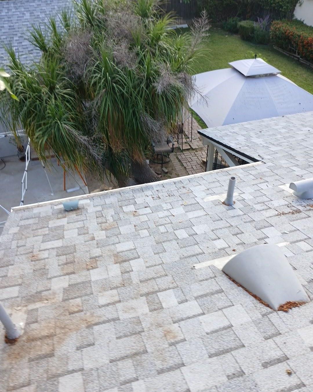 Heavily worn asphalt shingle roof in Los Angeles showing granule loss, pipe vents, and a roof vent prior to tear-off