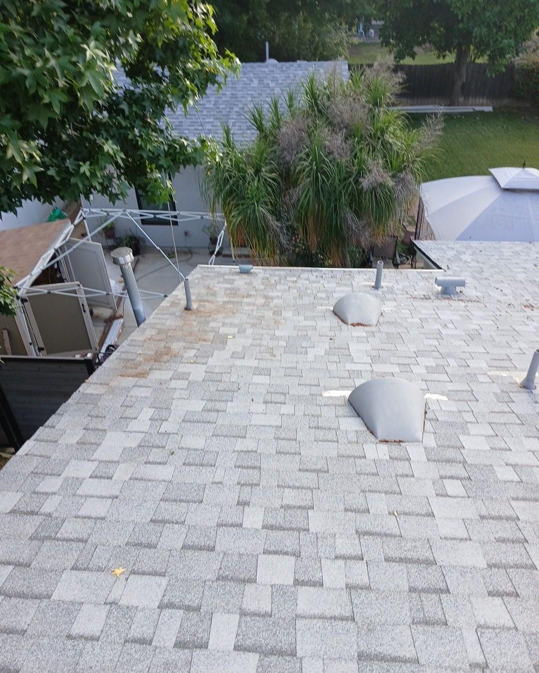 shingle-reroof-6643-saloma-ave-los-angeles-661 Residential gray asphalt shingle roof with two pipe boot flashings, vent stacks, and rust staining near pipes.