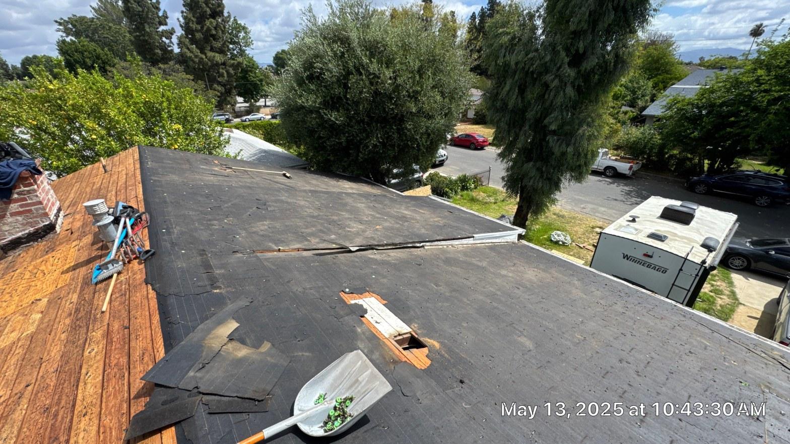 shingle-reroof-6643-saloma-ave-los-angeles-673 Roof tear-off in progress showing bare OSB decking, black underlayment, removed skylight opening, and tools on residential home.