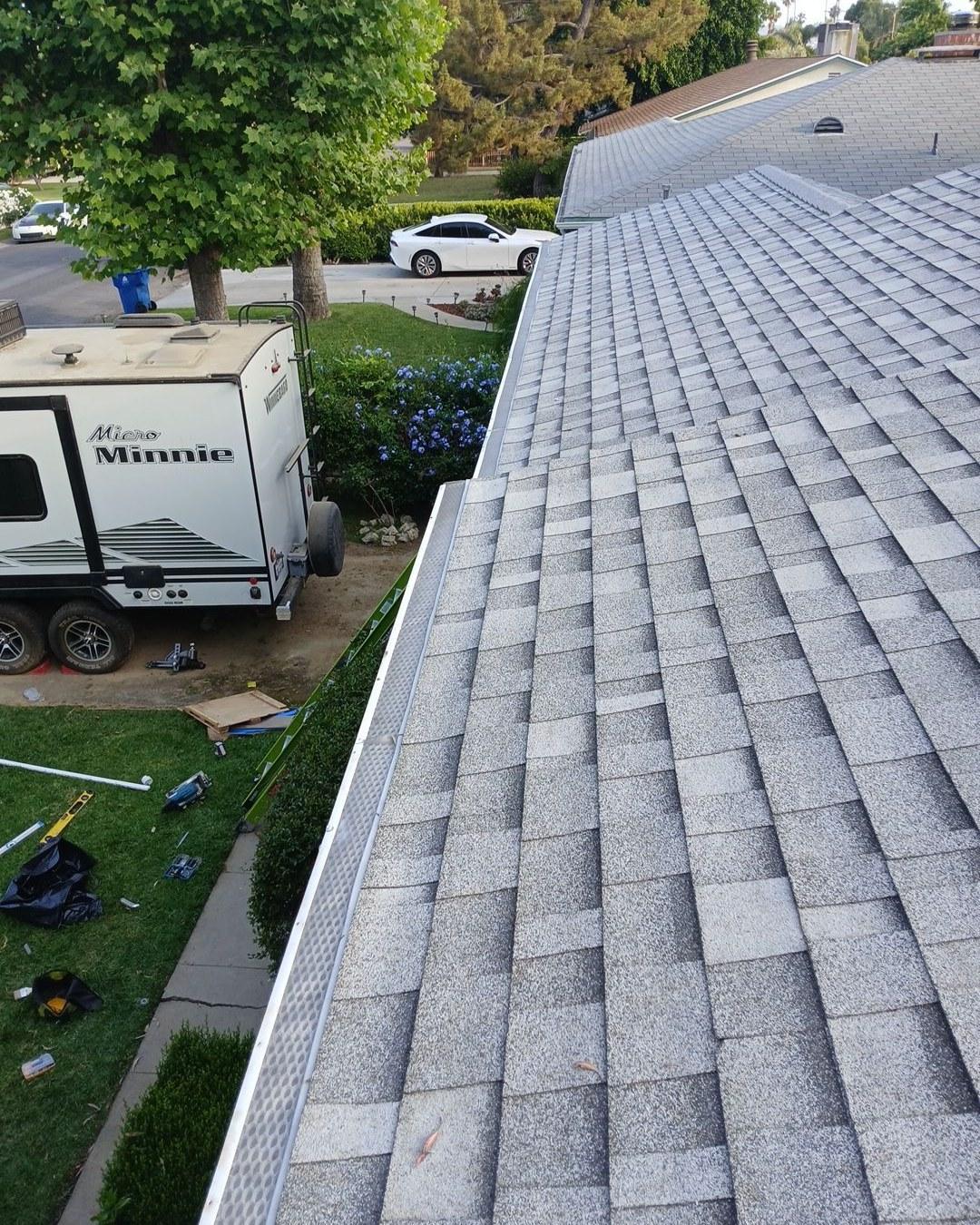 shingle-reroof-6643-saloma-ave-los-angeles-677 Freshly installed gray asphalt shingle roof with white gutters, Micro Minnie trailer and Tesla visible below.