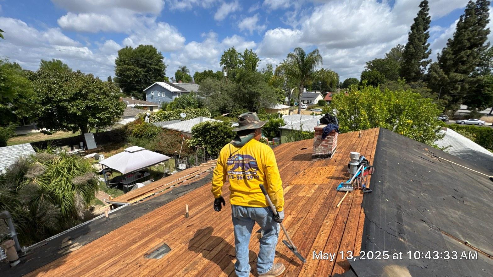 shingle-reroof-6643-saloma-ave-los-angeles-680 Roof Replacement Inc. worker in yellow shirt on exposed wood decking with chimney and tools visible.