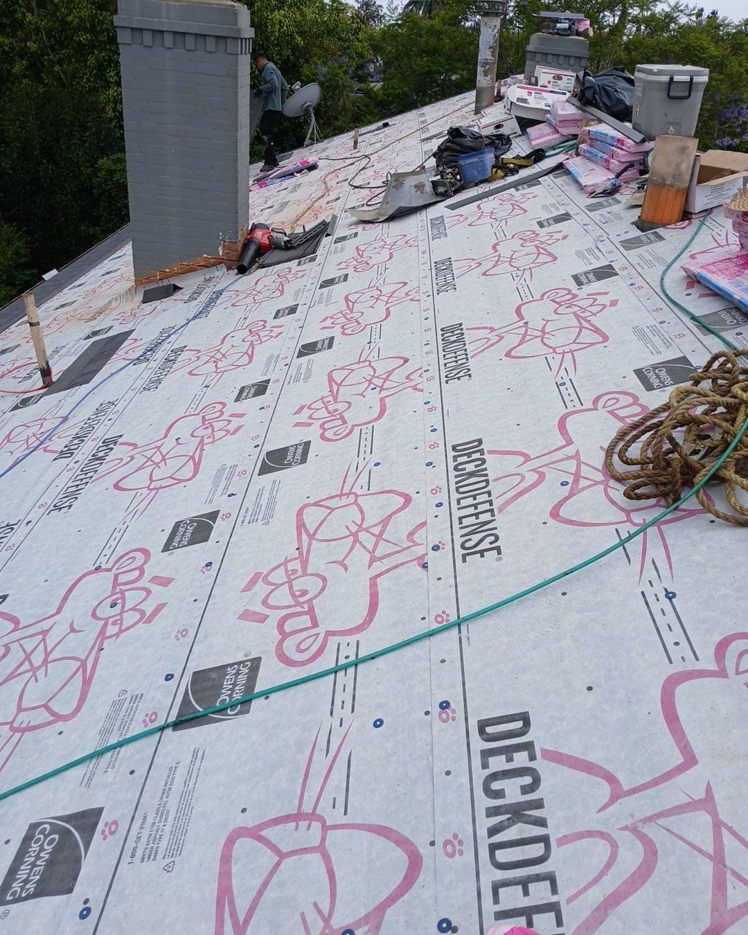 shingle-reroof-motor-ave-los-angeles-602 Owens Corning DeckDefense synthetic roof underlayment laid across full roof deck with worker and chimneys visible.
