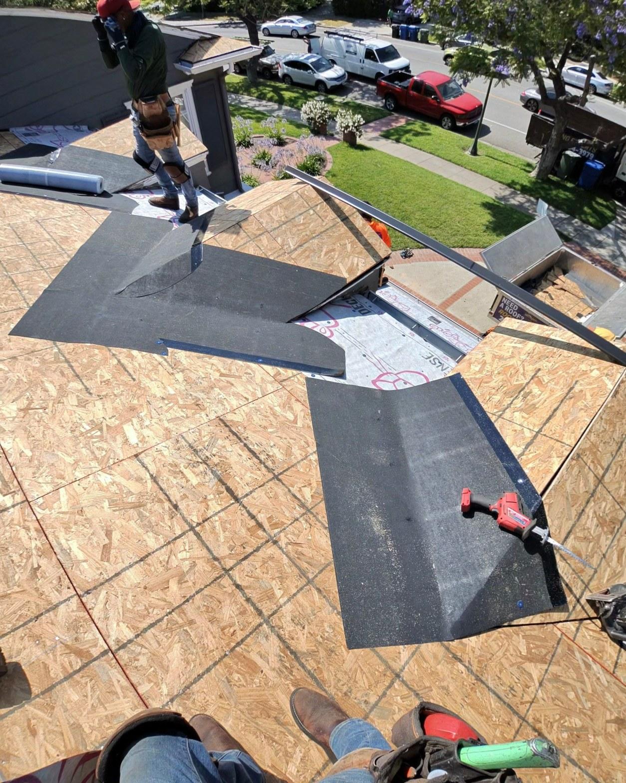 shingle-reroof-motor-ave-los-angeles-604 Aerial view of roofers laying black underlayment and metal flashing on OSB roof deck during re-roofing project.
