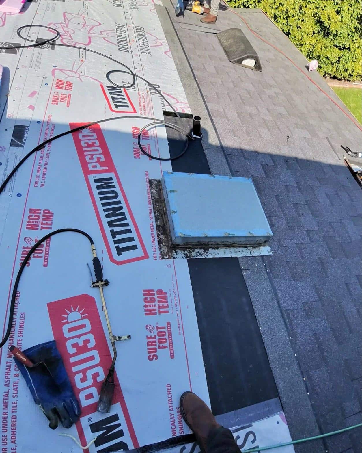 shingle-reroof-motor-ave-los-angeles-608 Roofers installing Titanium PSU30 high-temp underlayment around skylight opening on residential roof mid-replacement.