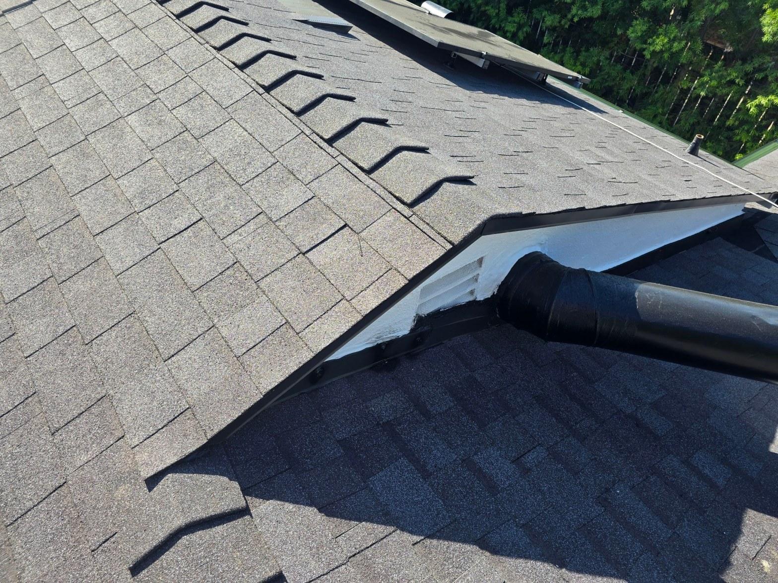 Asphalt shingle roof valley junction showing black plumbing pipe boot, ridge vent flashing, and soffit vent detail.