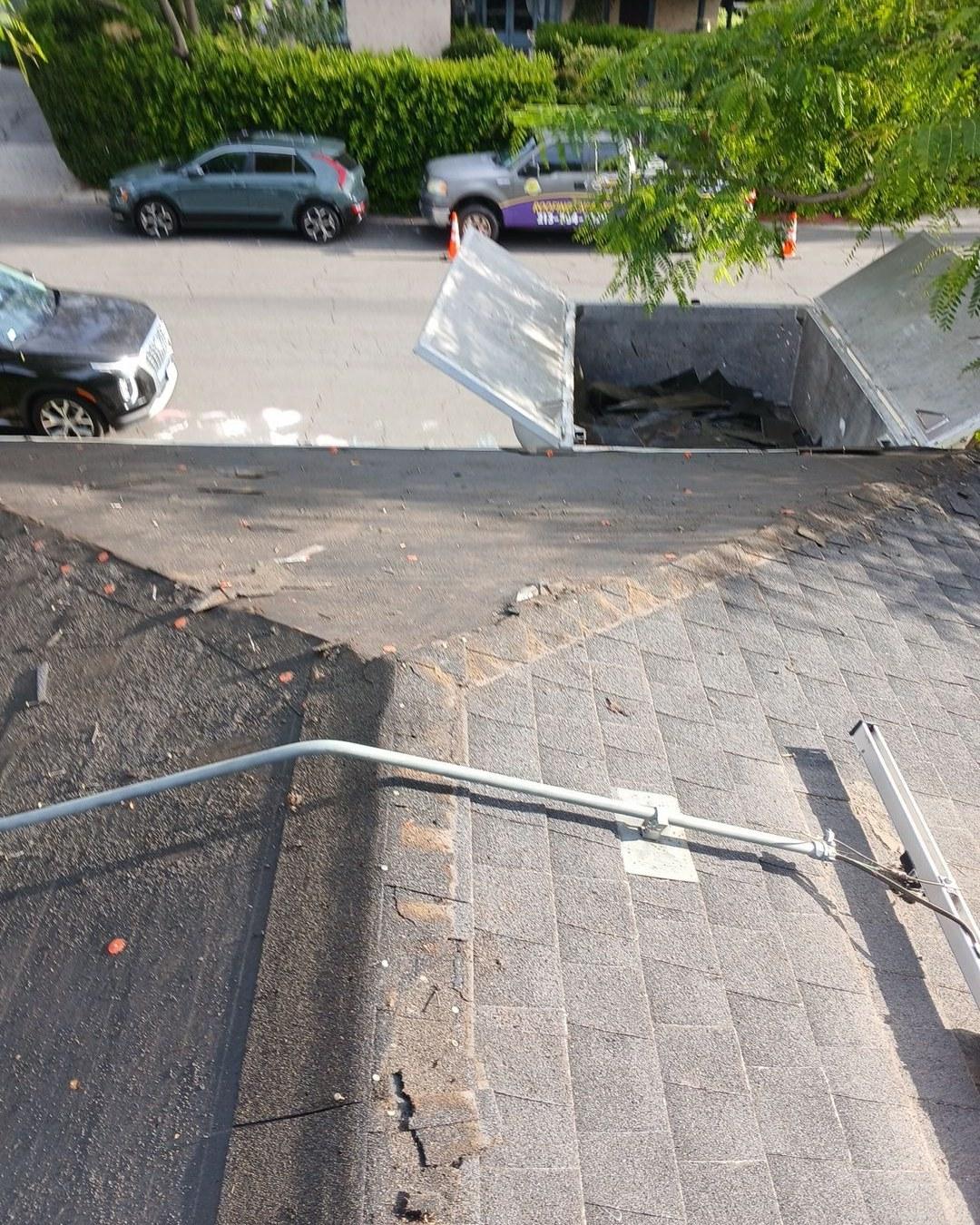 shingle-reroof-solar-complex-flashing-los-angeles-644 Rooftop view of deteriorated asphalt shingles, exposed underlayment, and open debris dumpster on building edge.