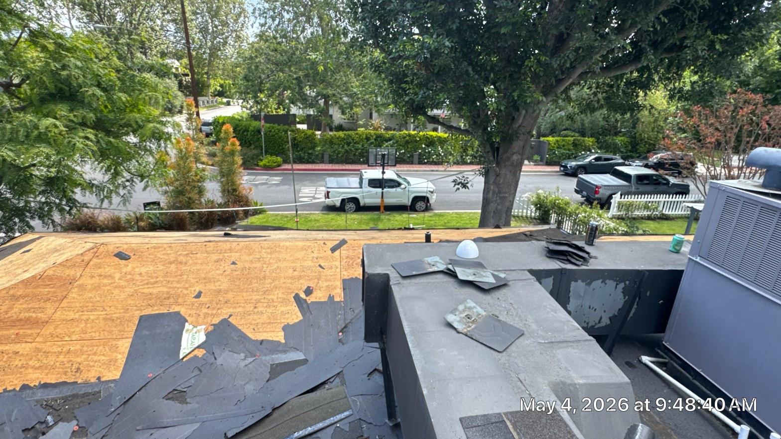 shingle-reroof-solar-complex-flashing-los-angeles-650 Roof tear-off in progress showing exposed OSB decking with torn asphalt shingles scattered on flat roof section below.