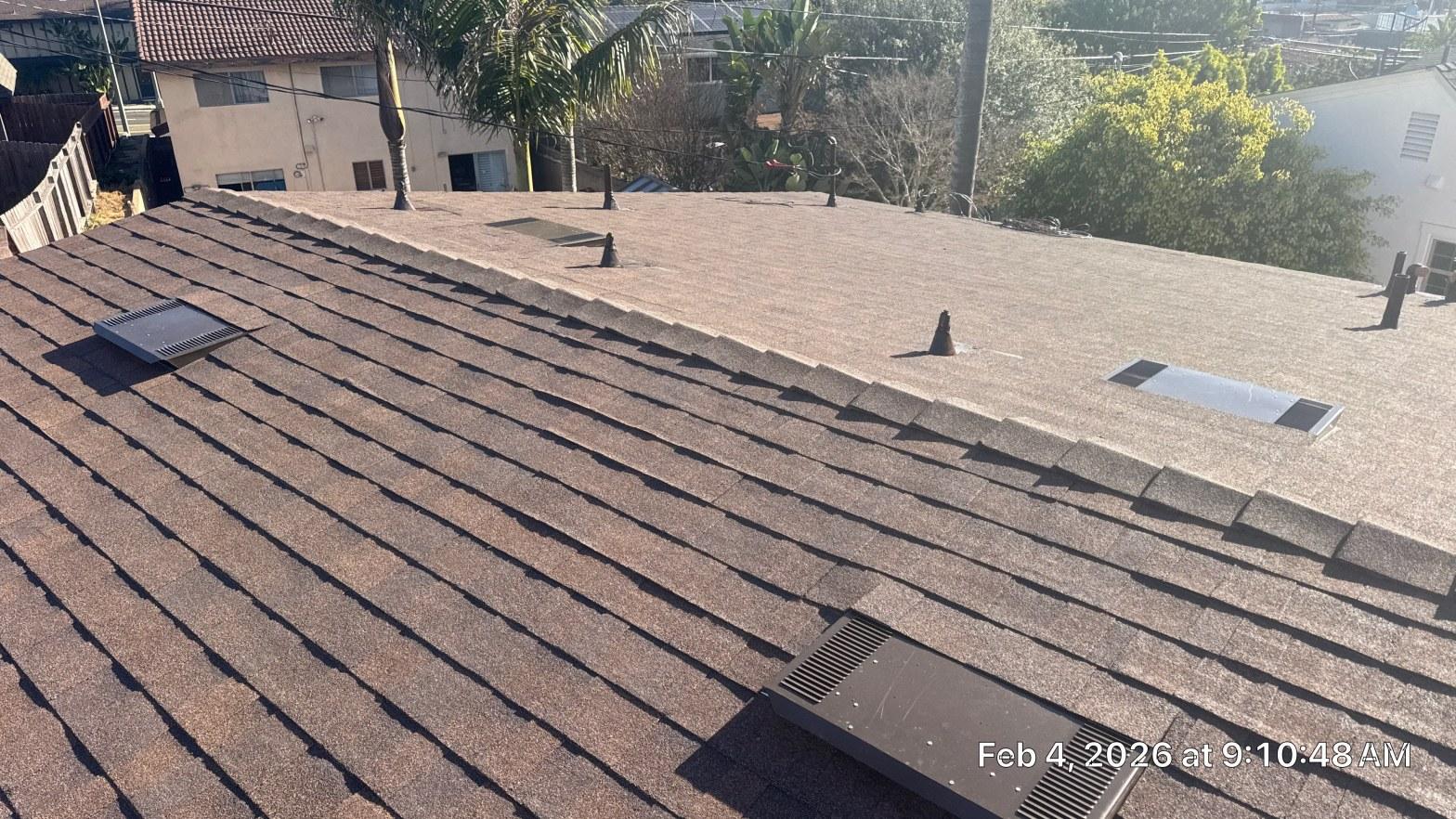 Completed brown asphalt shingle roof installation with low-profile vents and pipe boots on residential home.
