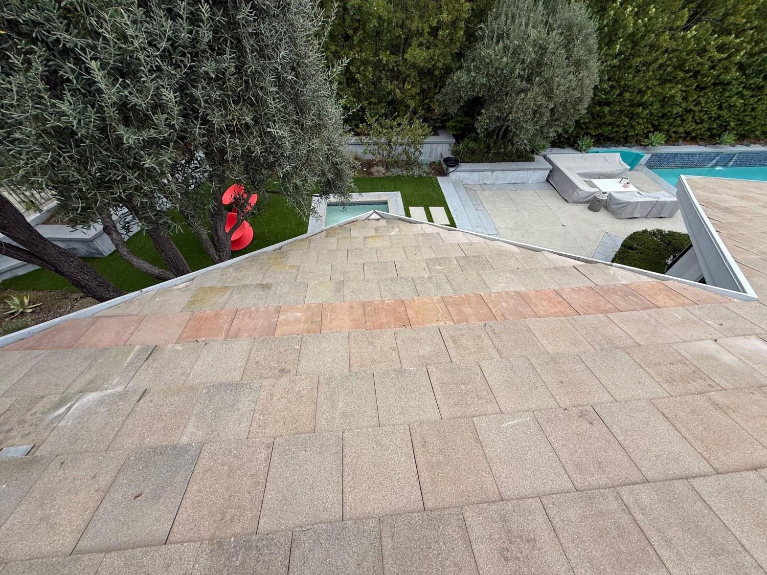 Aged asphalt shingle roof in Los Angeles with mismatched reddish replacement shingles showing prior unpermitted repair
