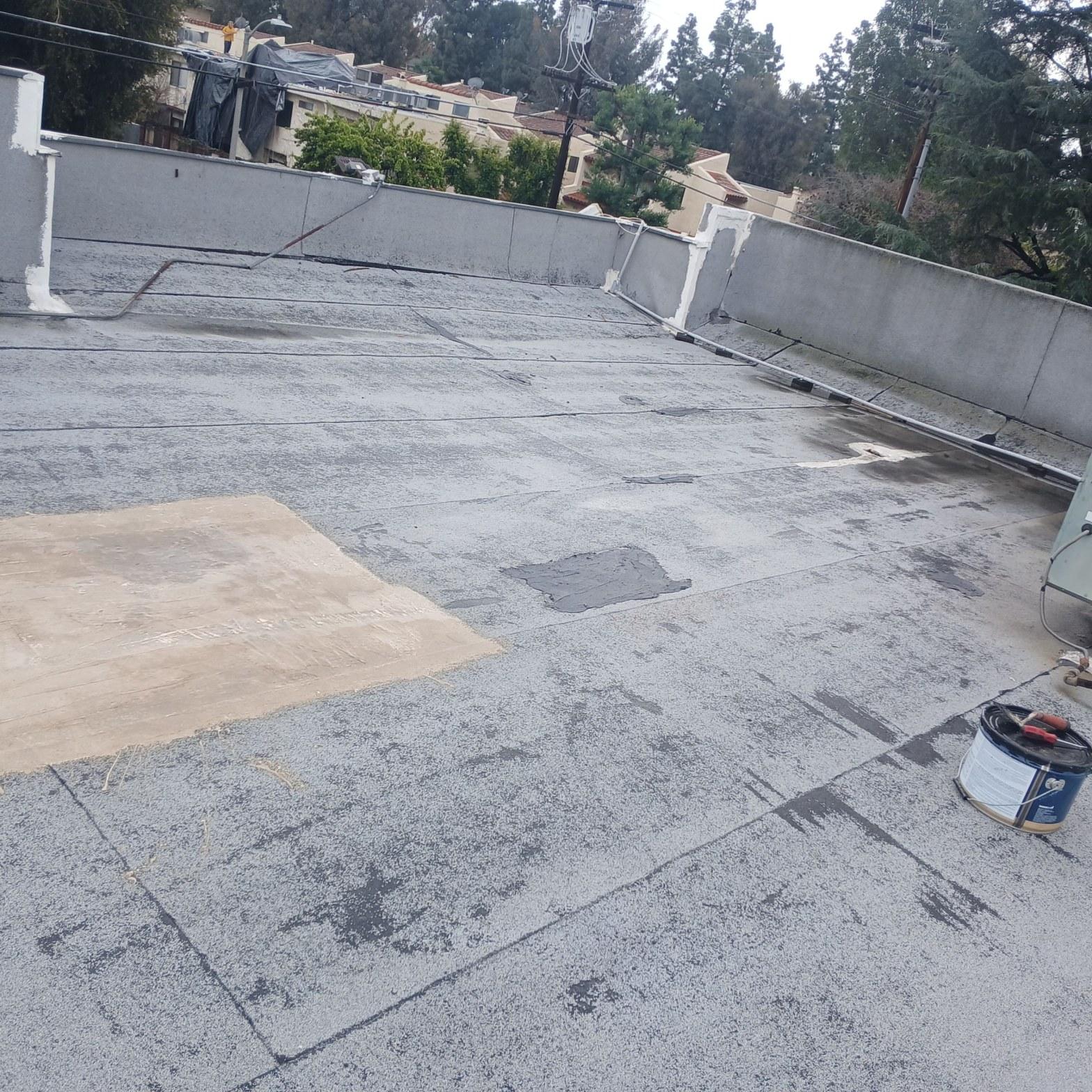 Worn torch down flat roof with bituminous patch areas and exposed substrate visible, 8801 Willis Ave Los Angeles