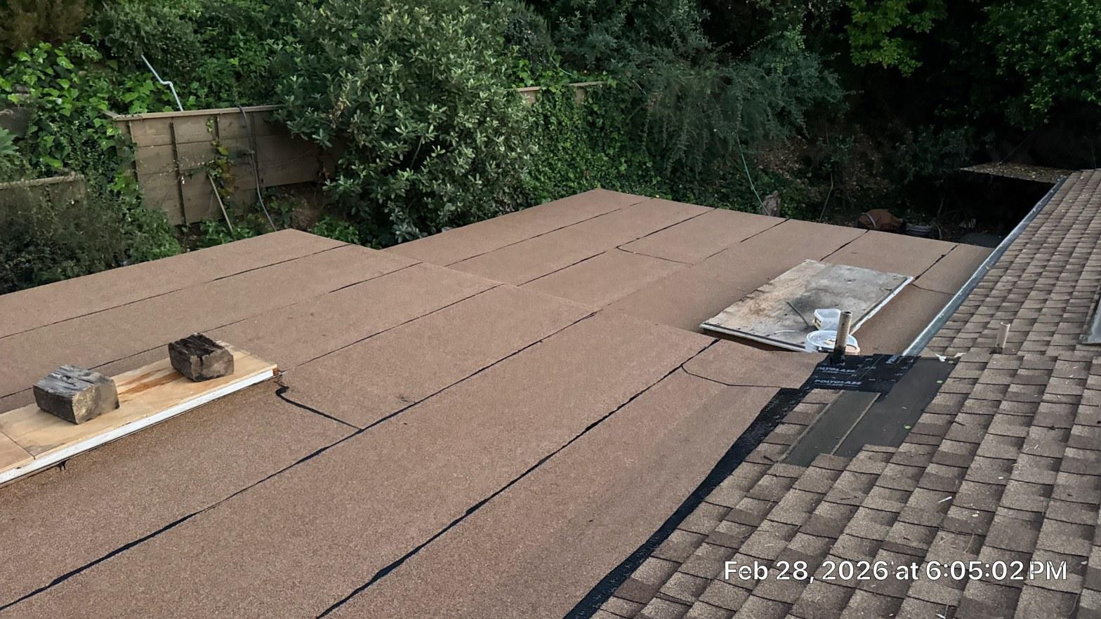 Flat roof covered with brown granulated felt underlayment sheets during torch-down replacement installation, Los Angeles CA