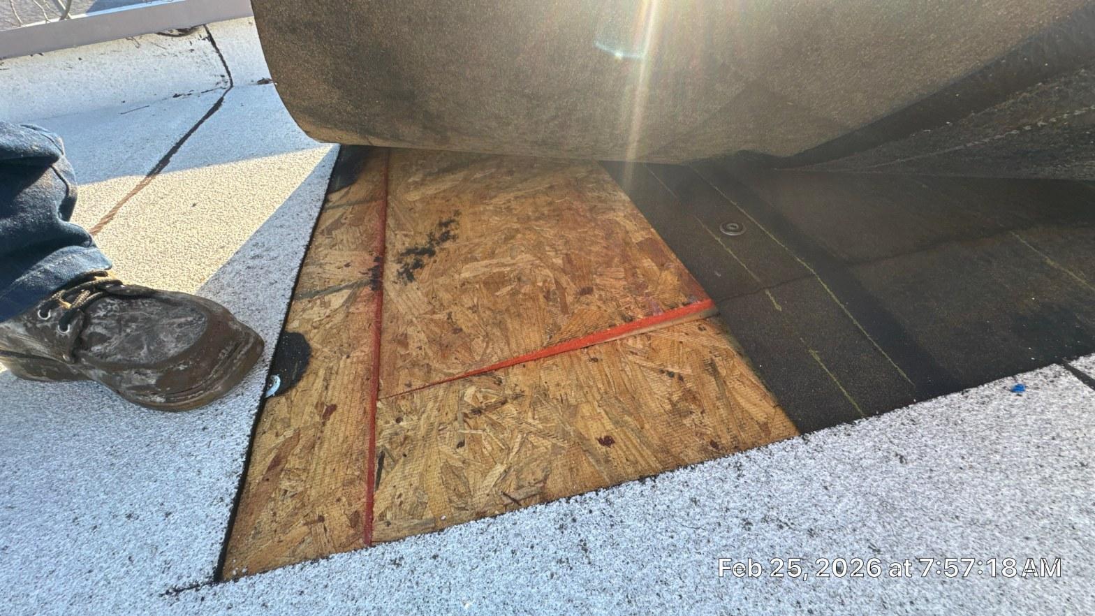 OSB plywood roof decking sheets with red chalk lines placed over black underlayment on flat roof edge.
