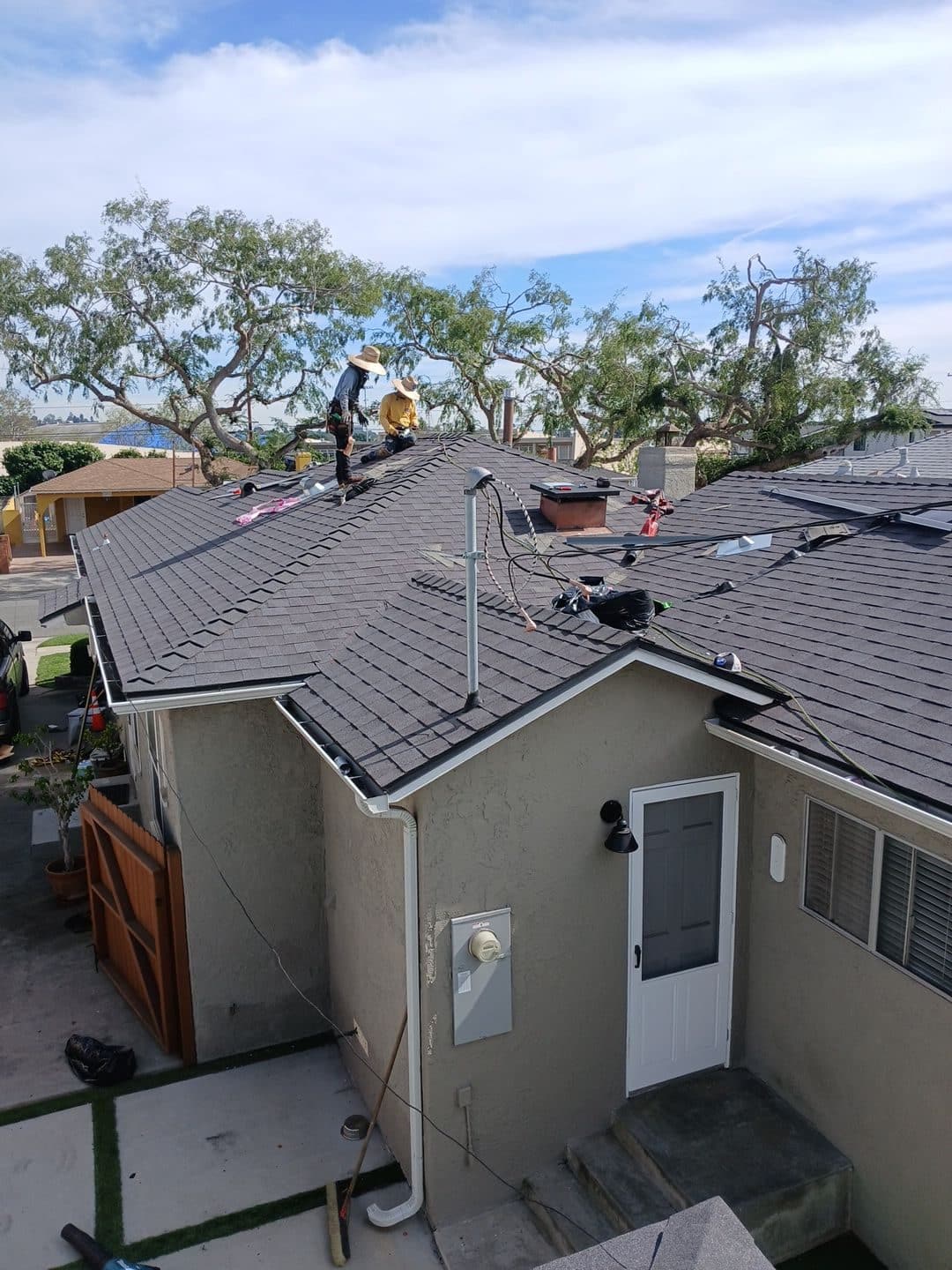 Two roofers installing dark asphalt shingles on hip roof | Roof Replacement Inc Two roofers installing dark asphalt shingles on hip roof — Roof Replacement Inc