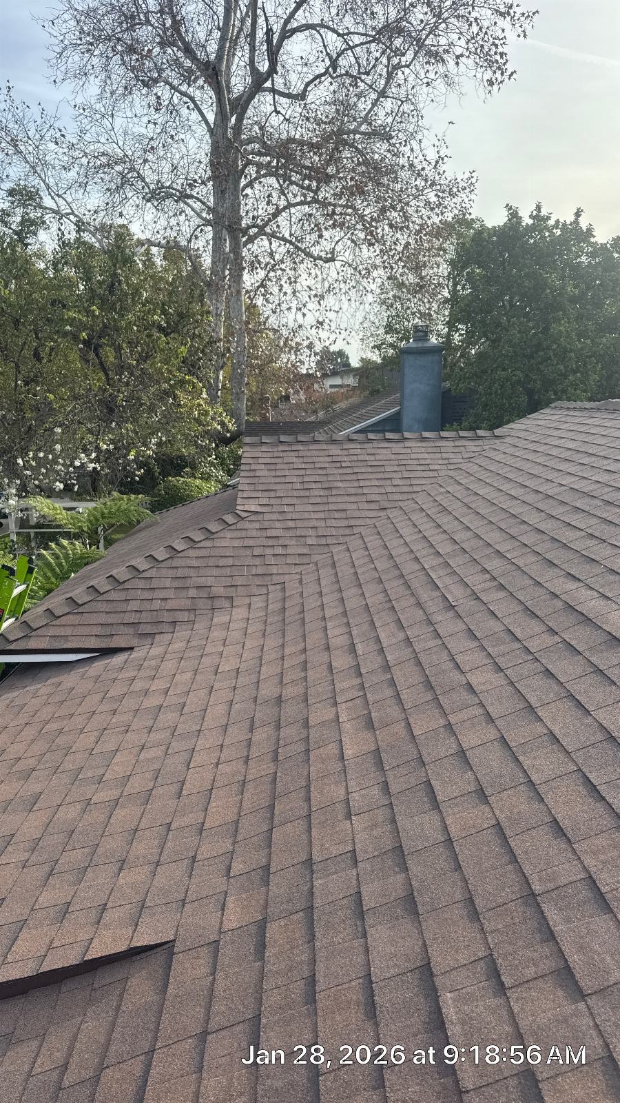 Completed asphalt shingle roof with hip ridges and metal chimney flue — Roof Replacement Inc
