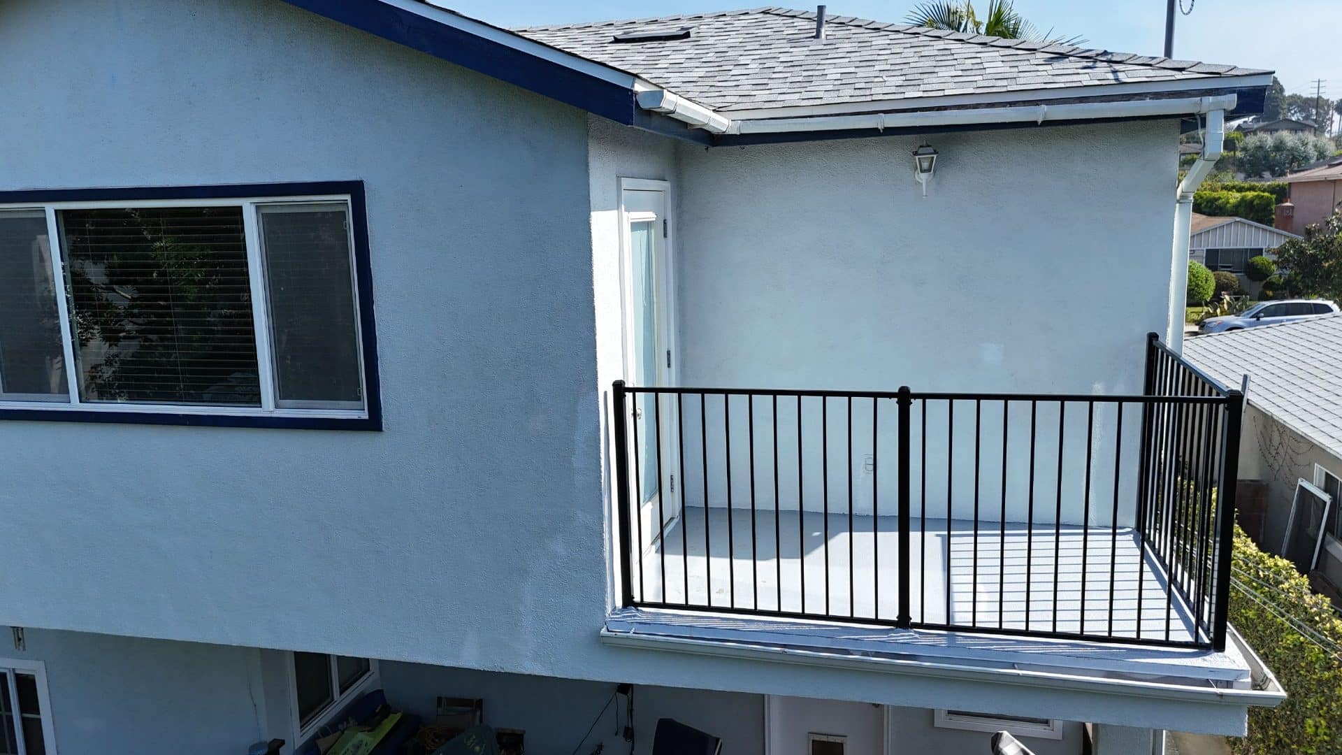 White stucco two-story house, asphalt shingle roof, second-floor balcony with black metal railing — Roof Replacement Inc