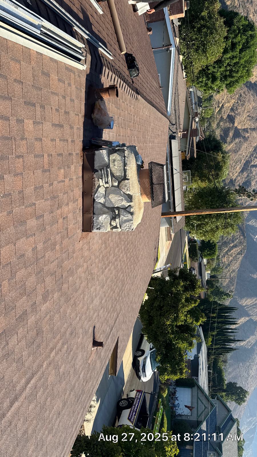 Brown asphalt shingle roof with open chimney chase and stone veneer — Roof Replacement Inc