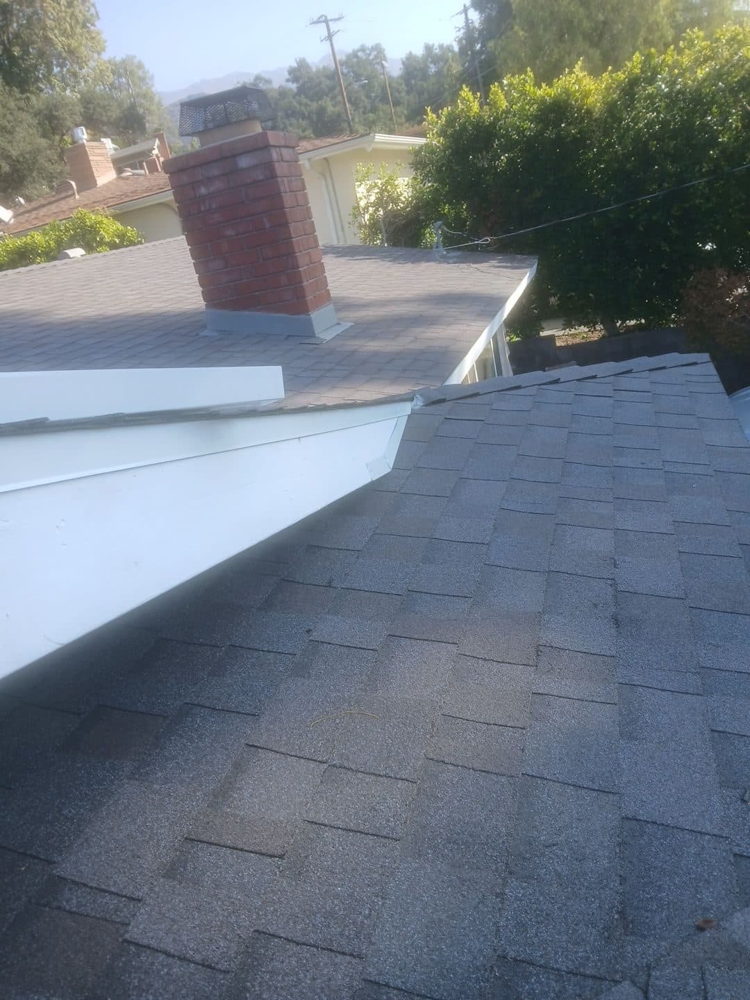Gray asphalt shingle roof with brick chimney and white fascia trim | Roof Replacement Inc Gray asphalt shingle roof with brick chimney and white fascia trim — Roof Replacement Inc