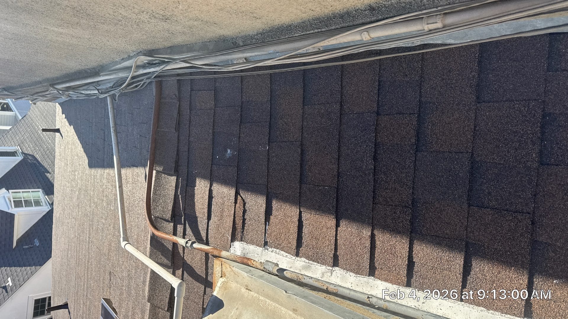 Dark asphalt shingles on sloped roof with copper downspout and gutter | Roof Replacement Inc Dark asphalt shingles on sloped roof with copper downspout and gutter — Roof Replacement Inc