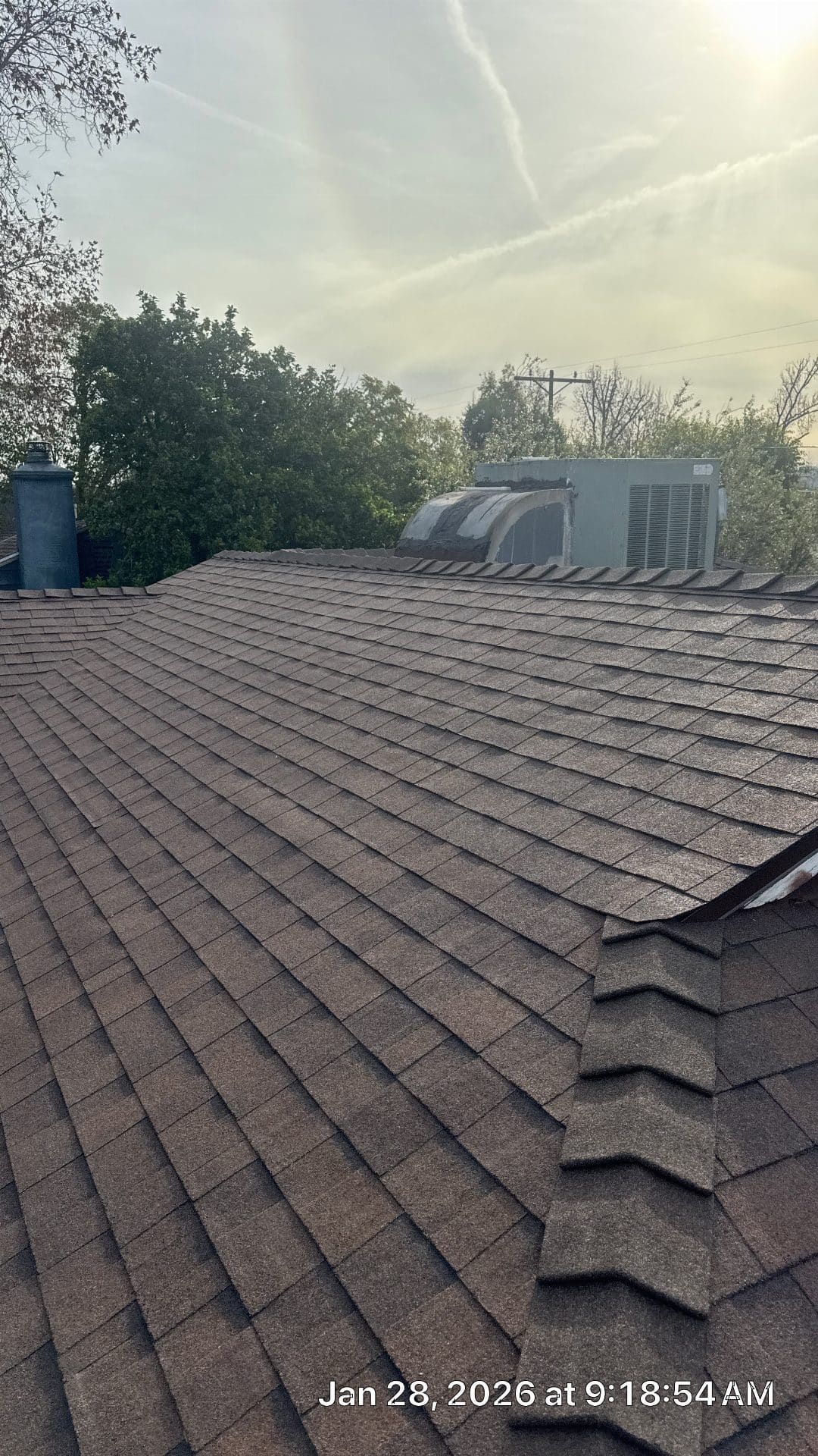 Brown asphalt shingle roof with chimney and rooftop HVAC unit | Roof Replacement Inc Brown asphalt shingle roof with chimney and rooftop HVAC unit — Roof Replacement Inc