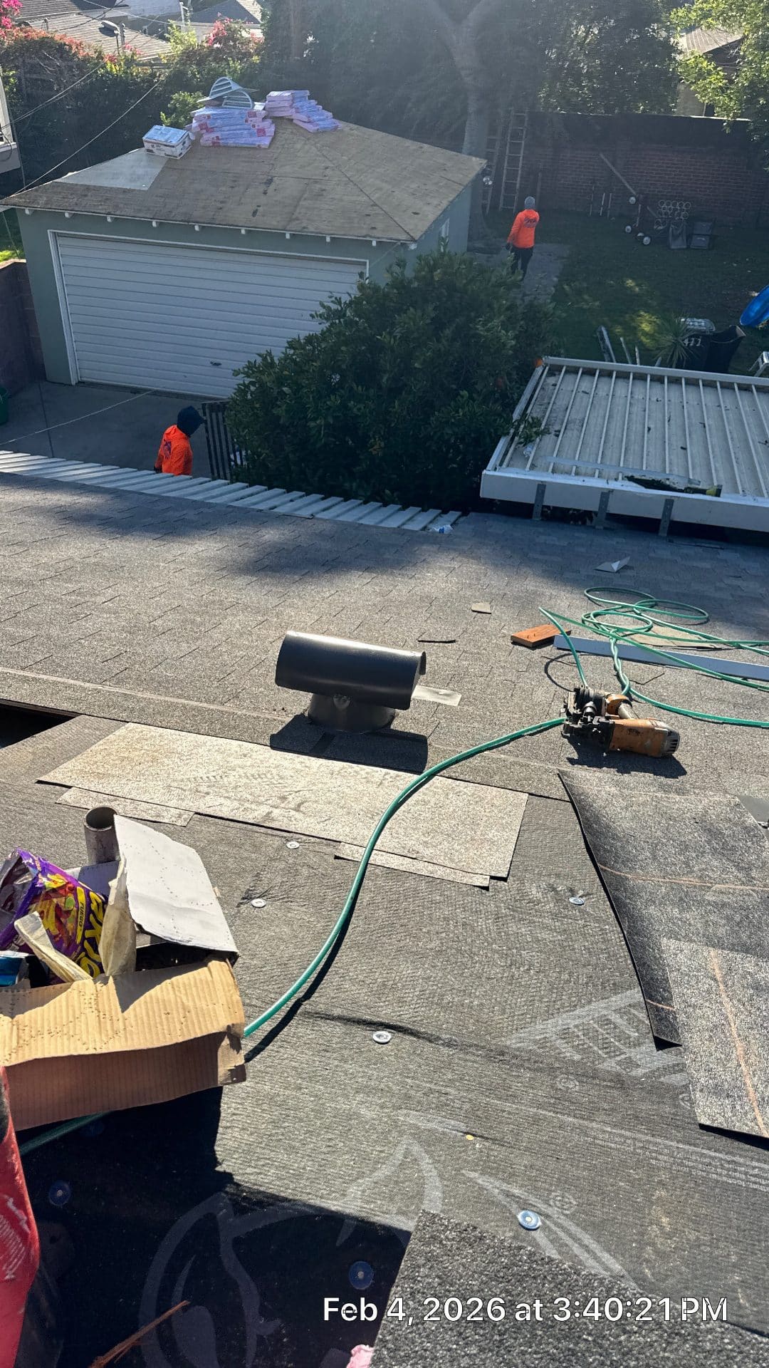 Workers installing asphalt shingles on roof with nail gun and hose | Roof Replacement Inc workers installing asphalt shingles on roof with nail gun and hose — Roof Replacement Inc