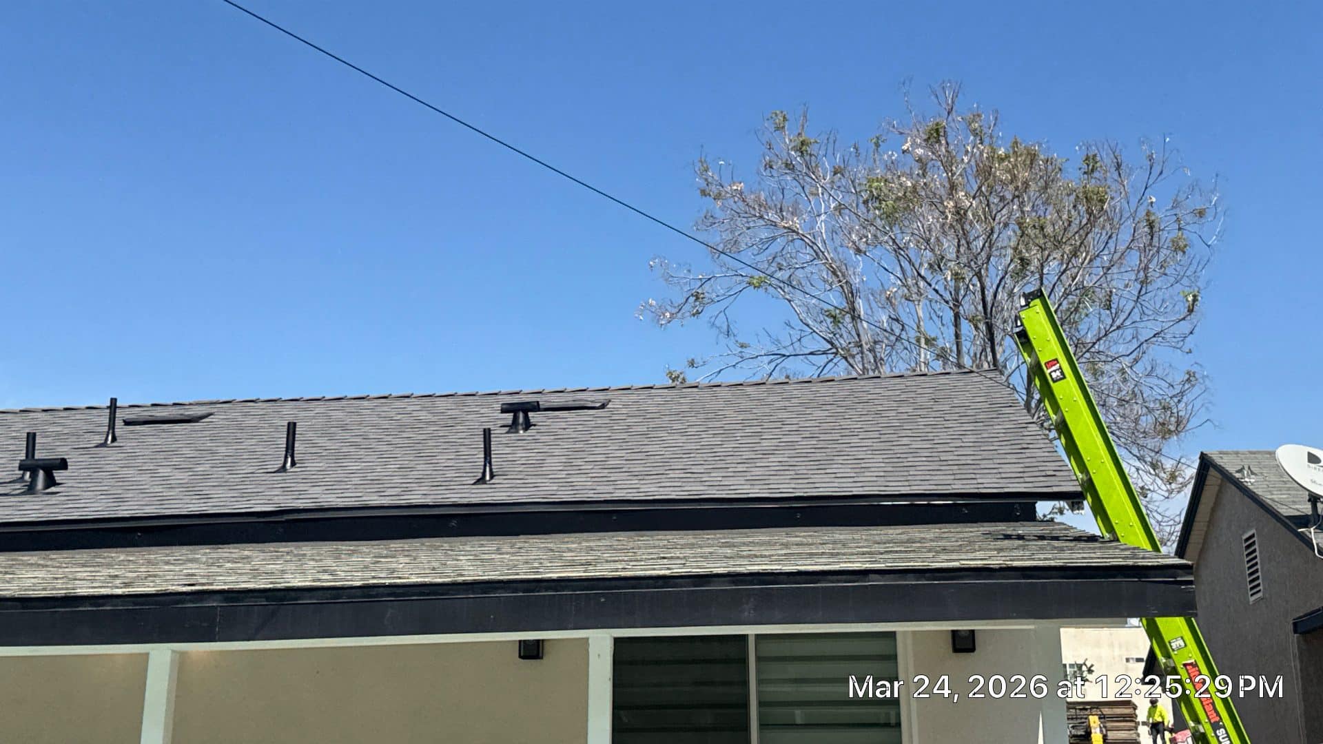 Newly installed asphalt shingle roof with pipe boots and green extension ladder — Roof Replacement Inc