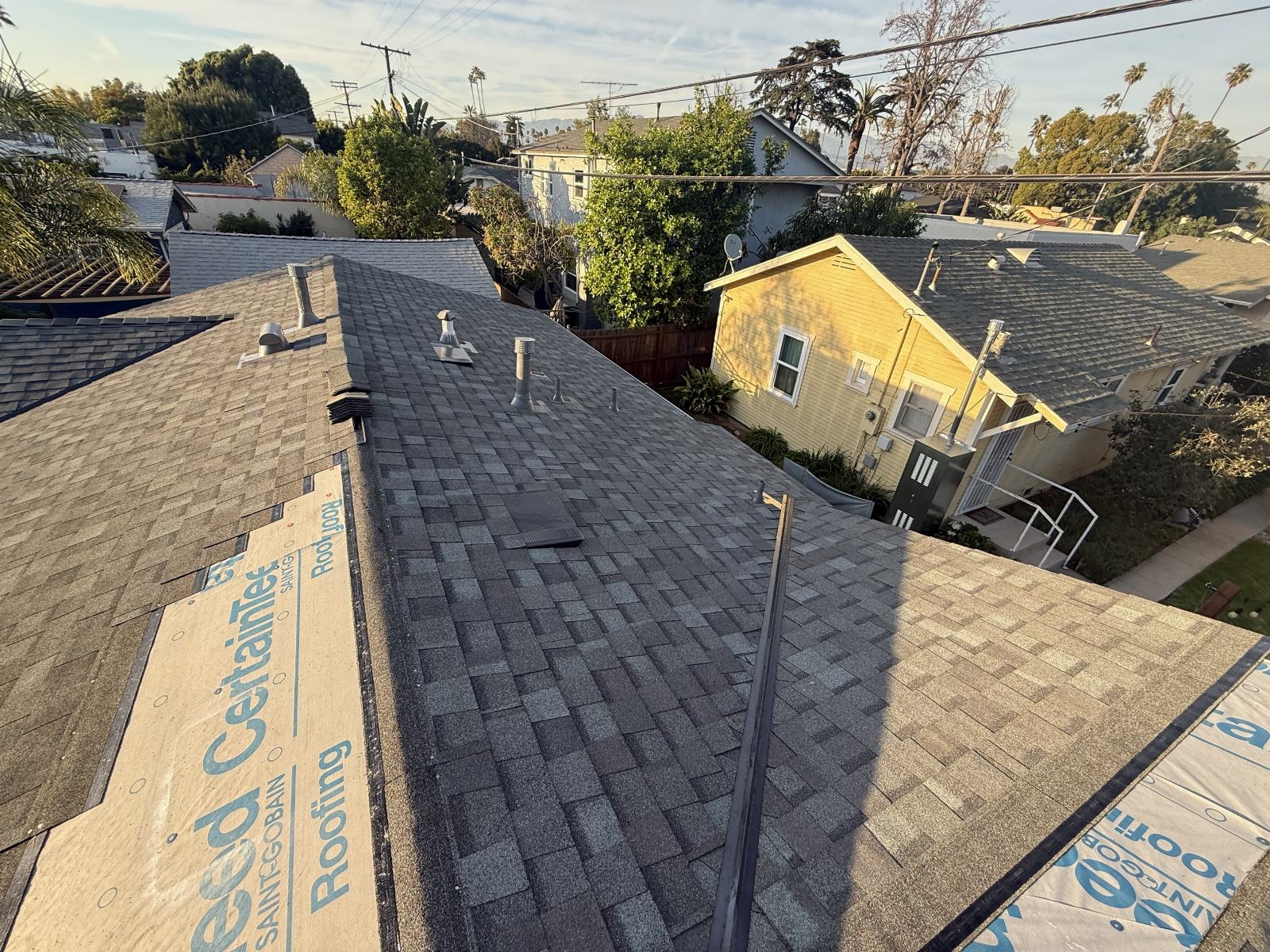 New asphalt shingle roof with pipe boots and roofing underlayment visible | Roof Replacement Inc new asphalt shingle roof with pipe boots and roofing underlayment visible — Roof Replacement Inc