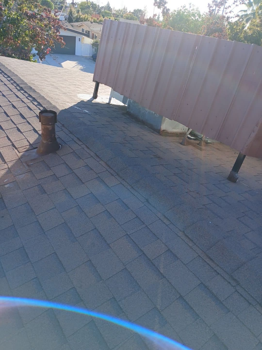 Asphalt shingle roof with pipe boots, corrugated metal fence panel — Roof Replacement Inc