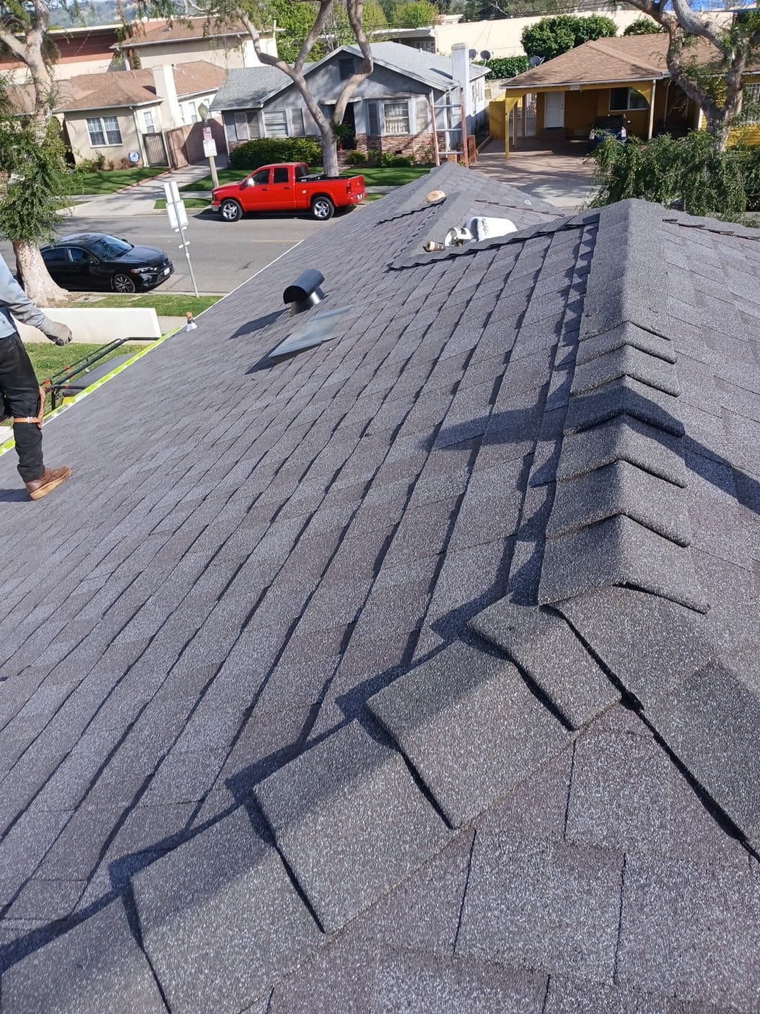 Newly installed dark gray asphalt shingle roof with ridge cap and pipe vents | Roof Replacement Inc Newly installed dark gray asphalt shingle roof with ridge cap and pipe vents — Roof Replacement Inc