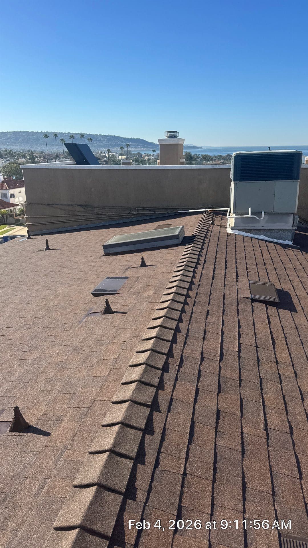 Brown asphalt shingle roof with ridge vent, skylights, roof vents, HVAC unit — Roof Replacement Inc