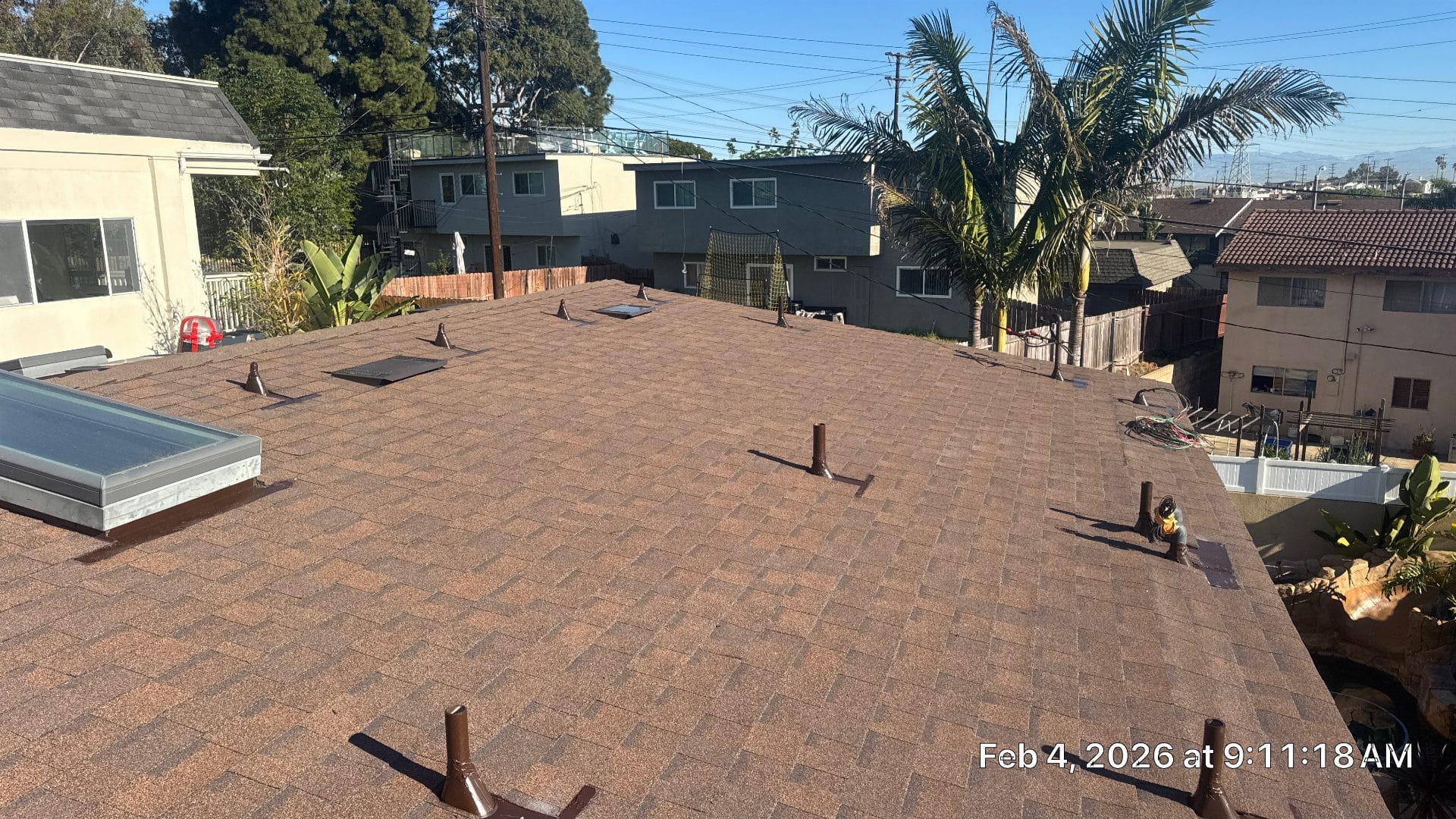 Completed brown asphalt shingle roof with skylight and pipe boots — Roof Replacement Inc