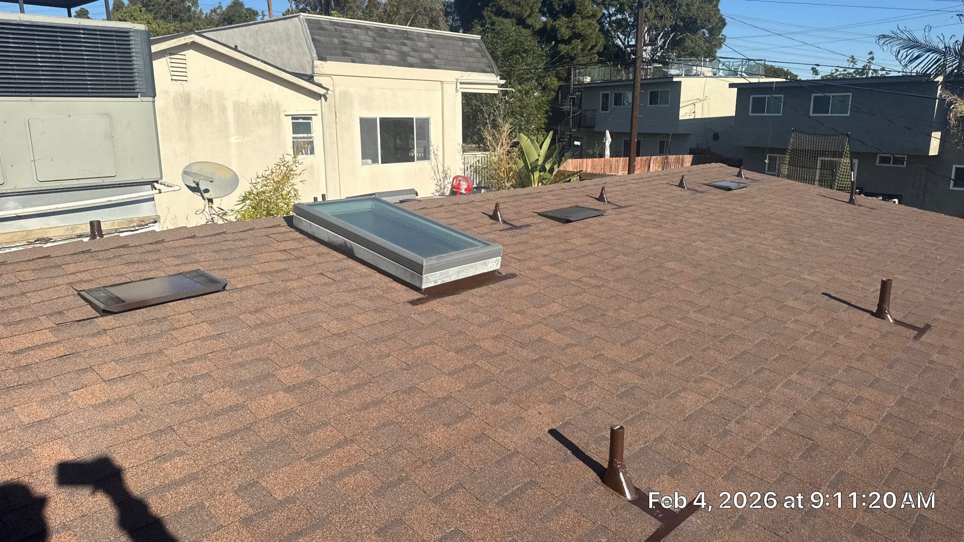 Brown asphalt shingle roof with skylight, vents, and pipe boots | Roof Replacement Inc Brown asphalt shingle roof with skylight, vents, and pipe boots — Roof Replacement Inc