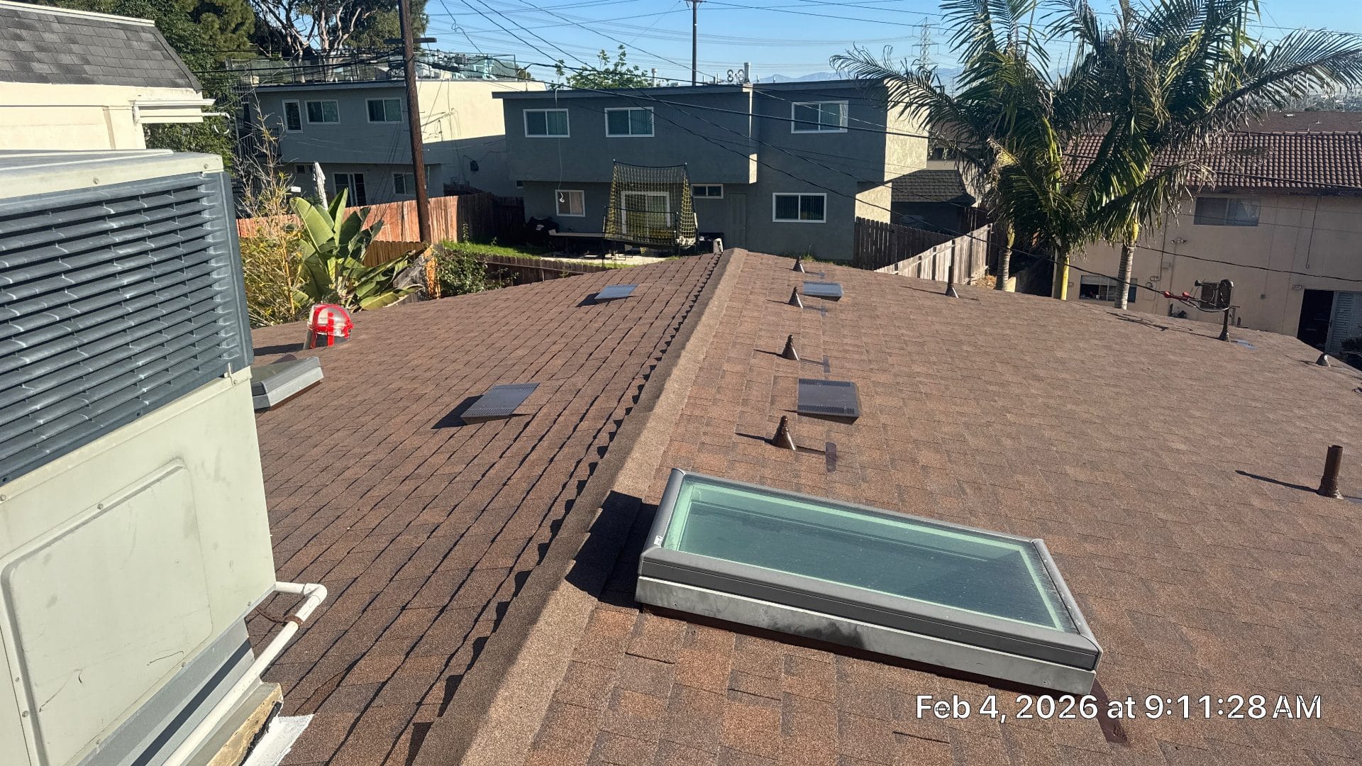 Brown asphalt shingle roof with multiple skylights and HVAC unit — Roof Replacement Inc