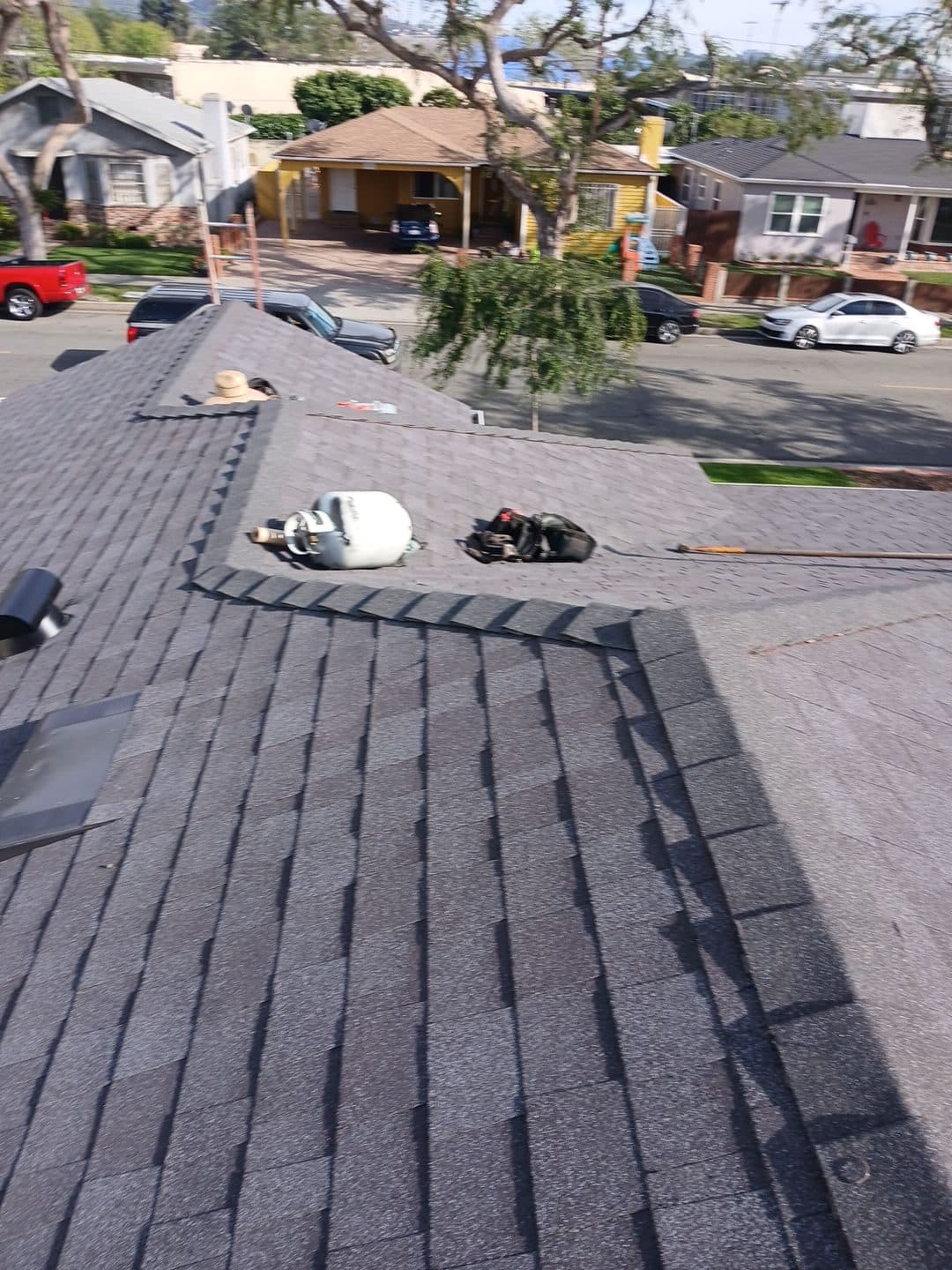Gray asphalt shingle roof with propane tank and torch equipment on ridge | Roof Replacement Inc Gray asphalt shingle roof with propane tank and torch equipment on ridge — Roof Replacement Inc