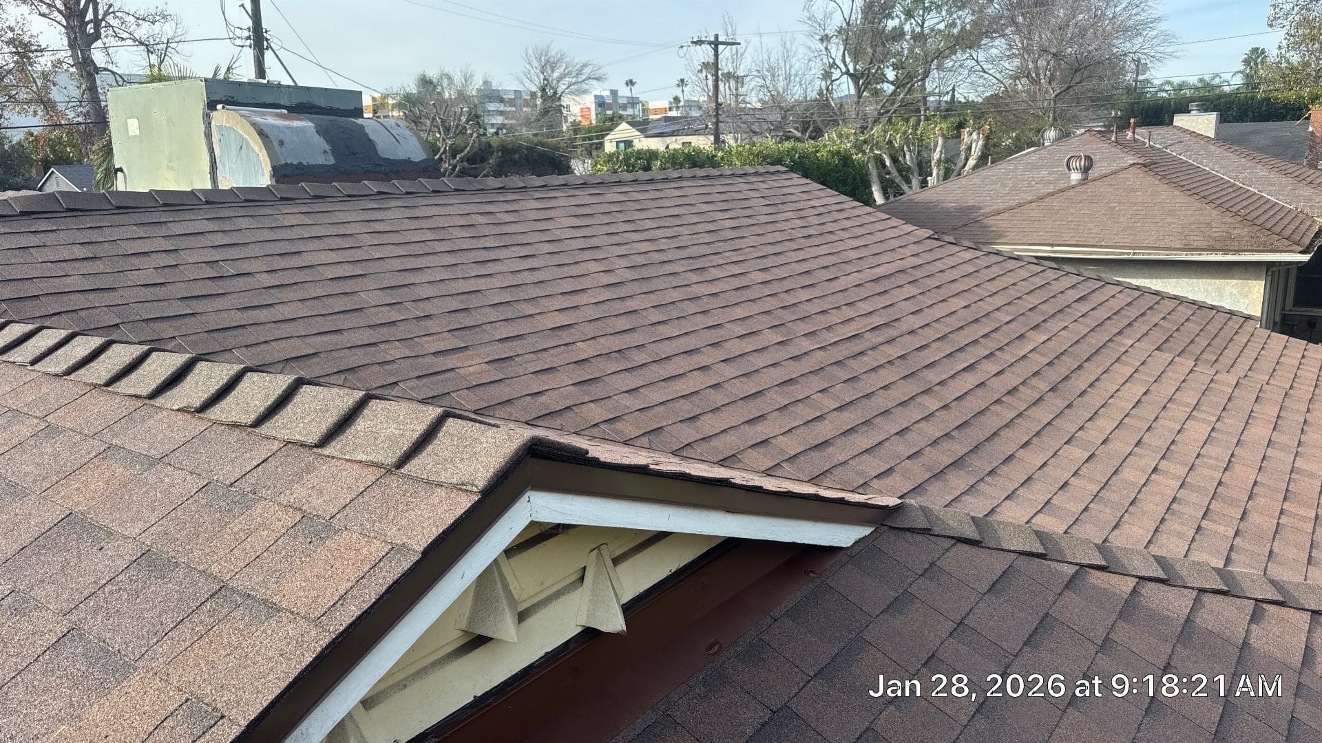 Brown asphalt shingle roof with valley, fascia, and solar water heater visible — Roof Replacement Inc